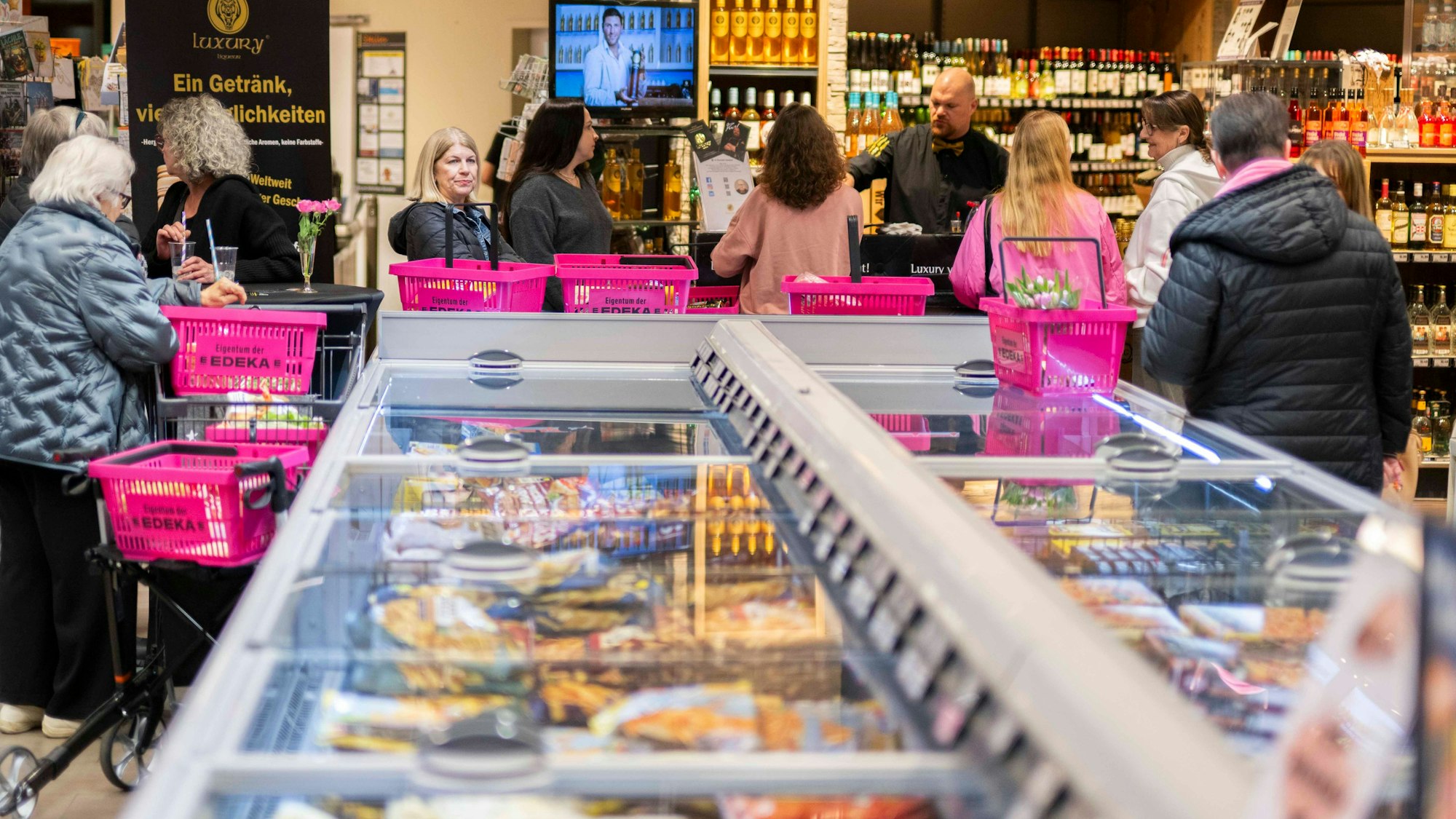 Das Bild zeigt zahlreiche rosa Einkaufskörbe, die auf der Kühltruhe stehen.