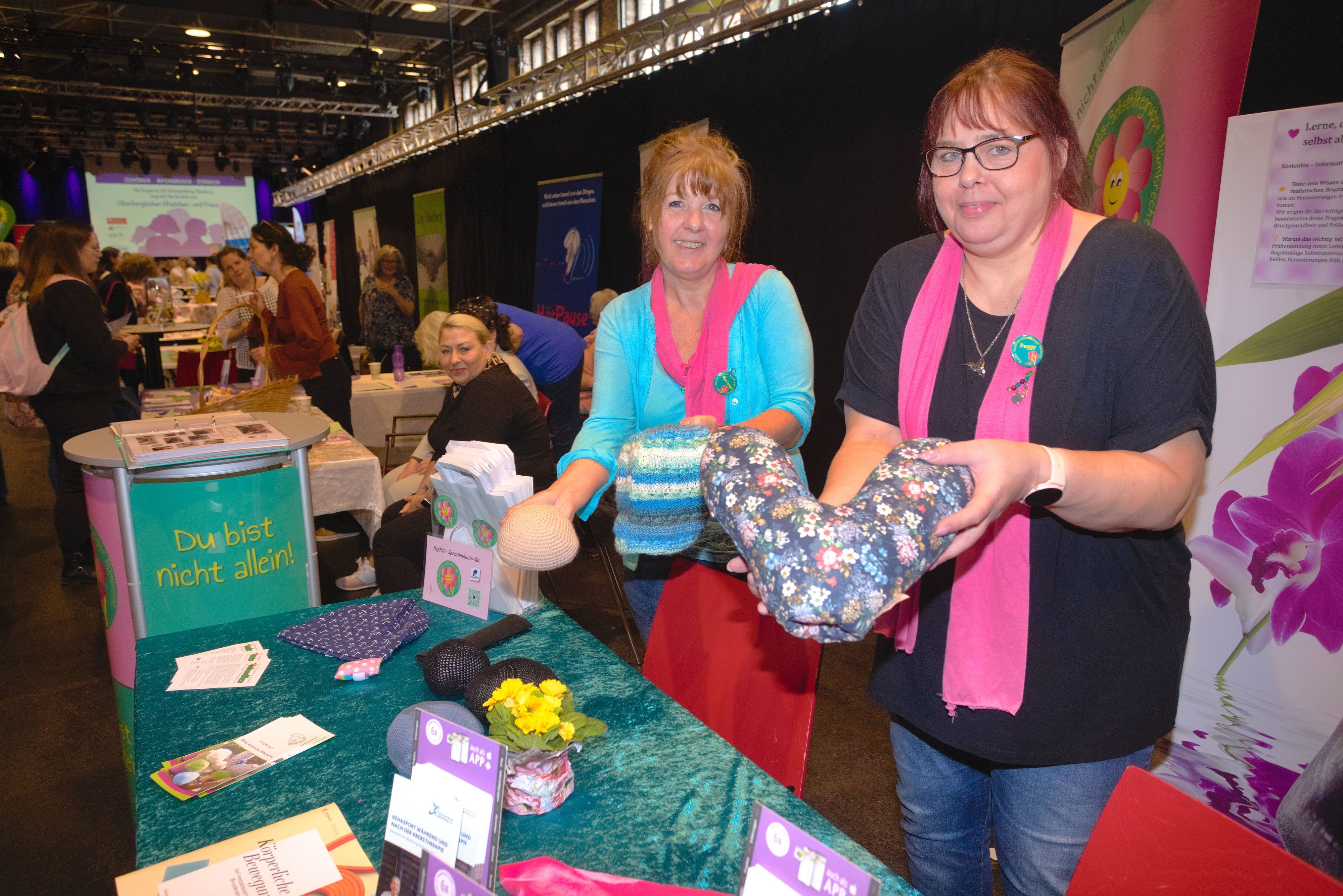 Zwei Frauen stehen an einem Stand einer Brustkrebs-Selbsthilfegruppe.