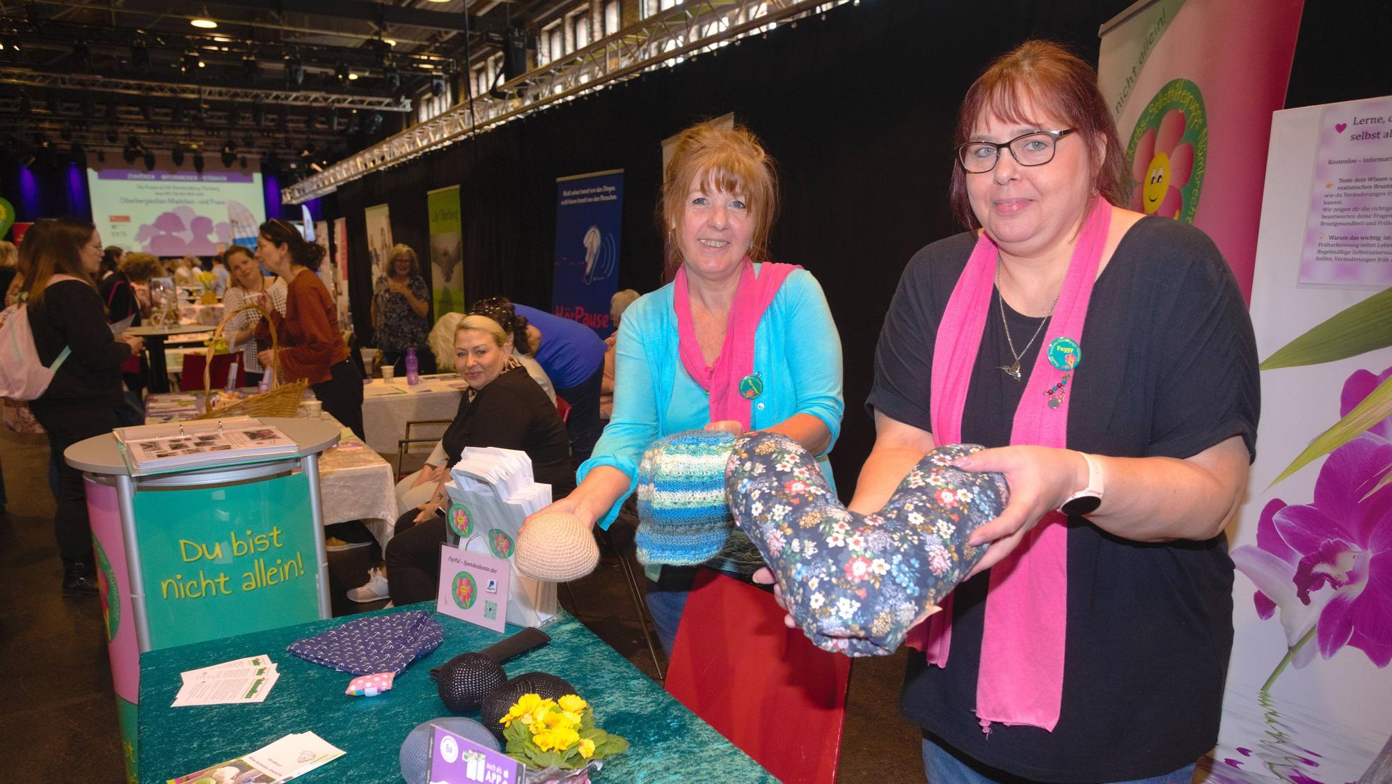 Zwei Frauen stehen an einem Stand einer Brustkrebs-Selbsthilfegruppe.