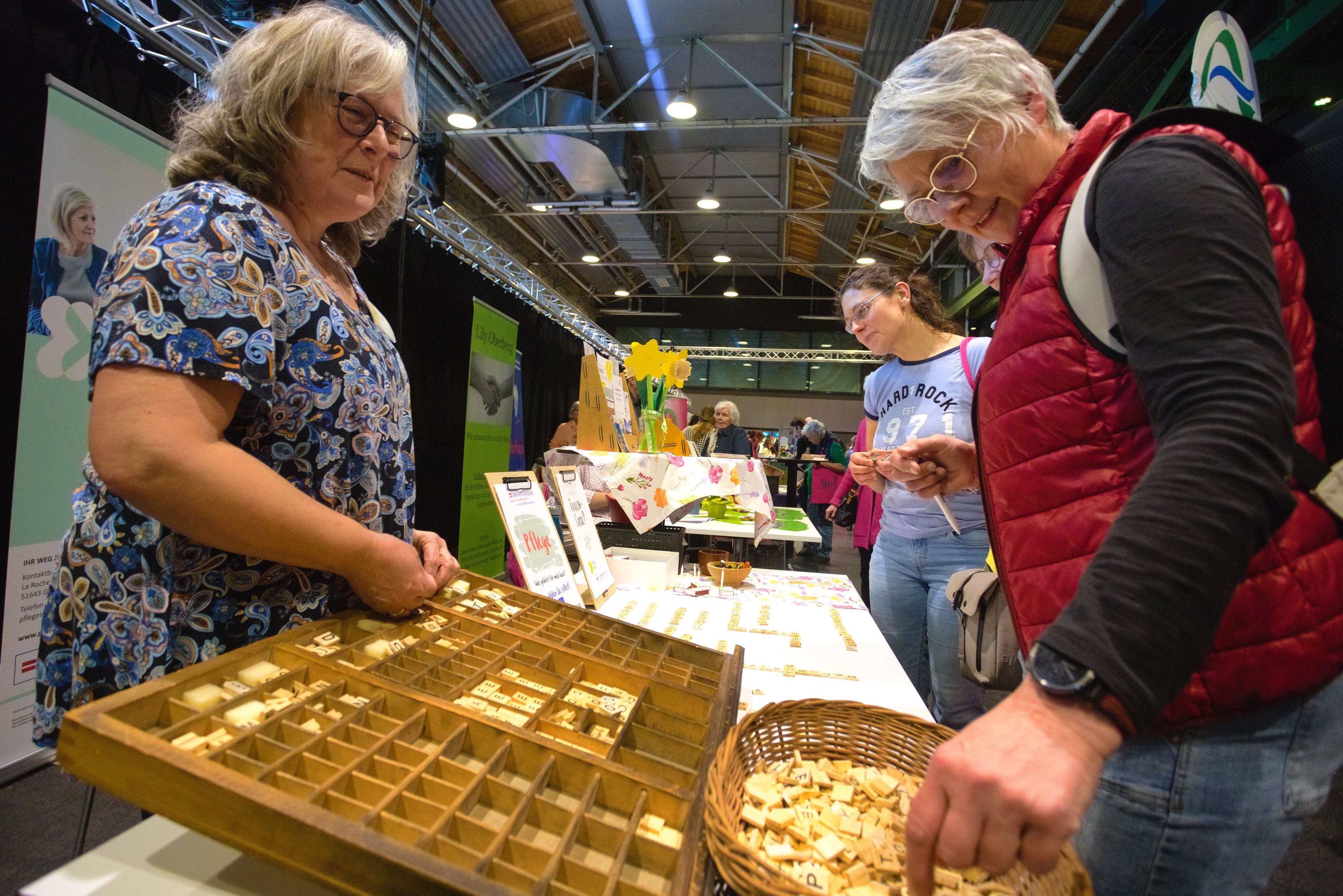 Am Stand des Kontaktbüros Pflegeselbsthilfe der Paritätischen lässt Dorit Knabe Besucherinnen aus Scrabble-Steinen Worte legen, die pflegenden Angehörigen durch den Kopf gehen.