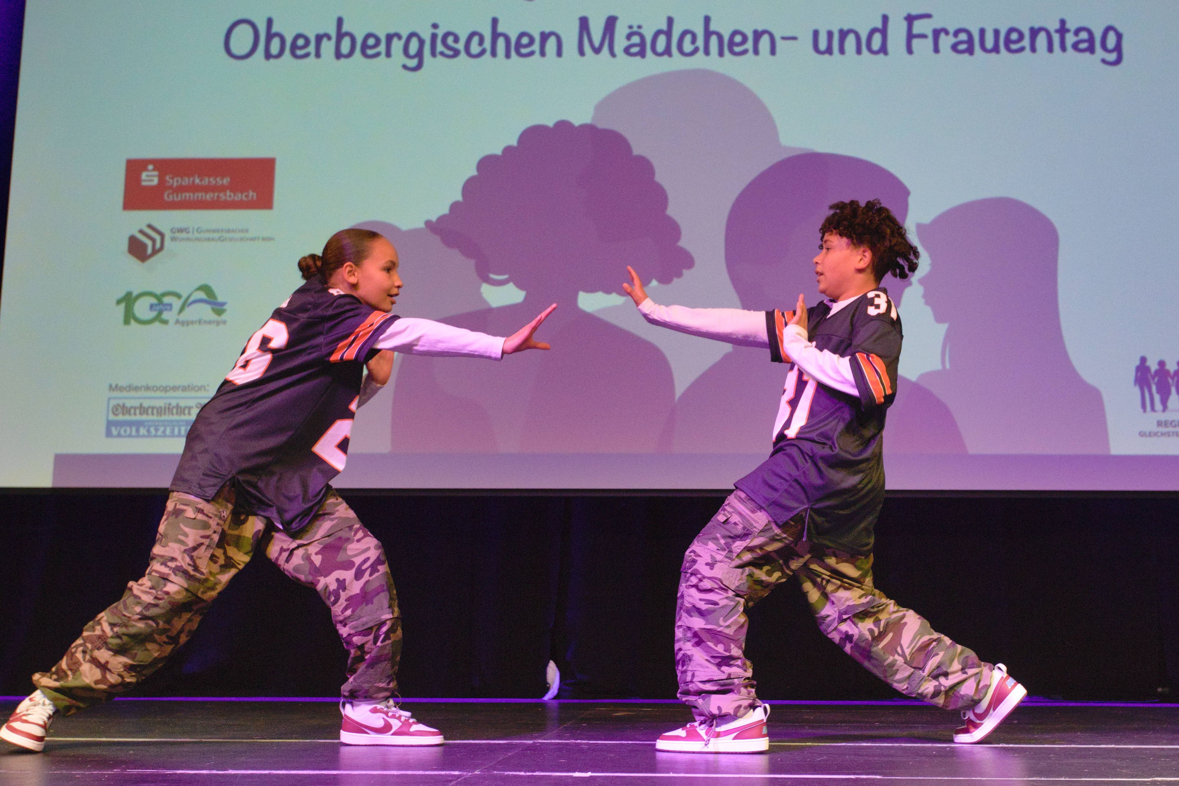 Zwei Geschwister tanzen Hip-Hop auf einer Bühne.