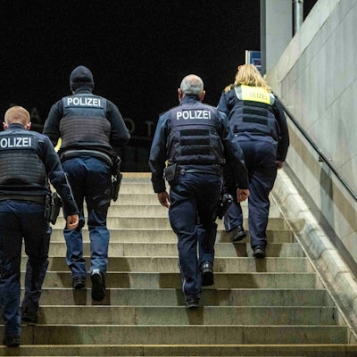 Fünf Menschen mit der Aufschrift „Polizei“ auf ihren Westen gehen eine Treppe hoch.