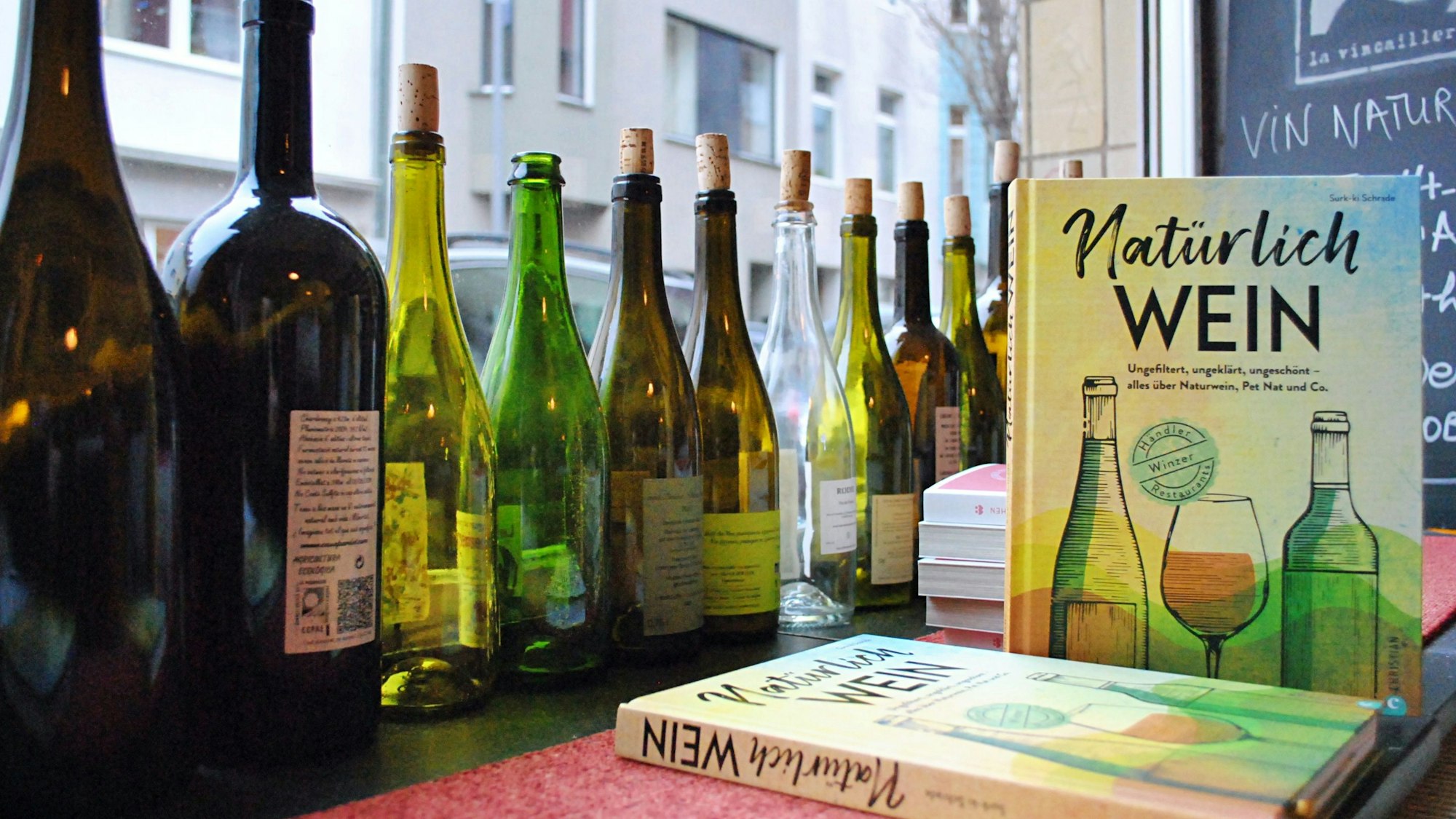 Flaschen und das Buch „Natürlich Wein“ stehen im Schaufenster eines Ladens.