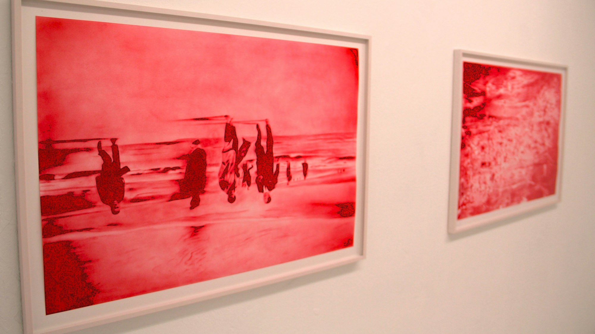 Zwei Bilder in Rottönen hängen nebeneinander.