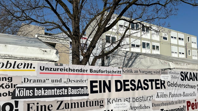 „Totalversagen“: Schlagzeilen zum Baudebakel finden sich am Zaun vor dem Offenbachplatz.