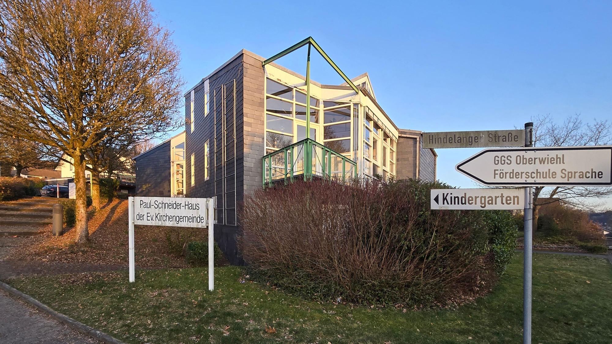 Außenansicht des Paul-Schneider-Hauses, davor Hinweisschilder zu den Schulen.