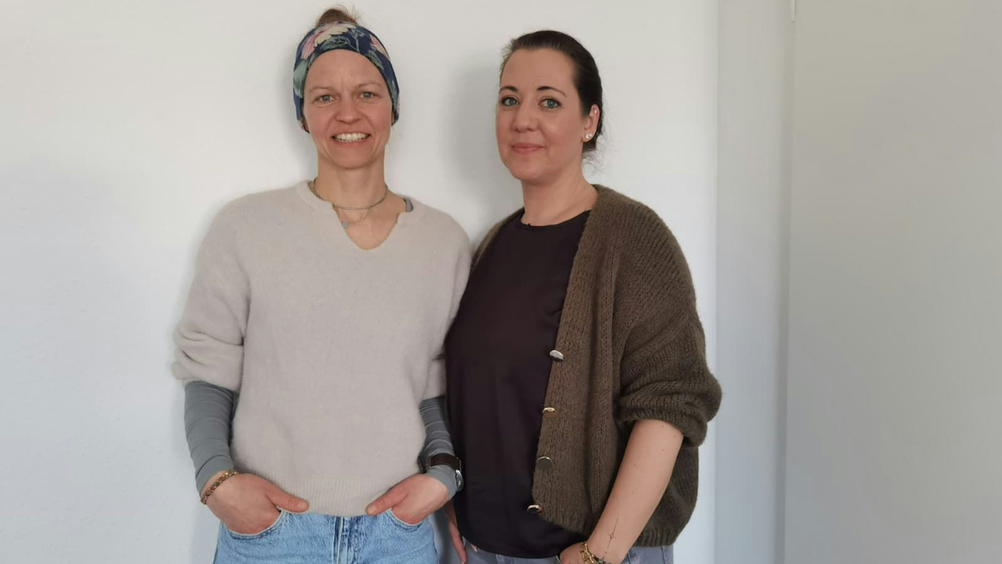 Zu sehen sind zwei Frauen, die lächelnd nebeneinander stehen.