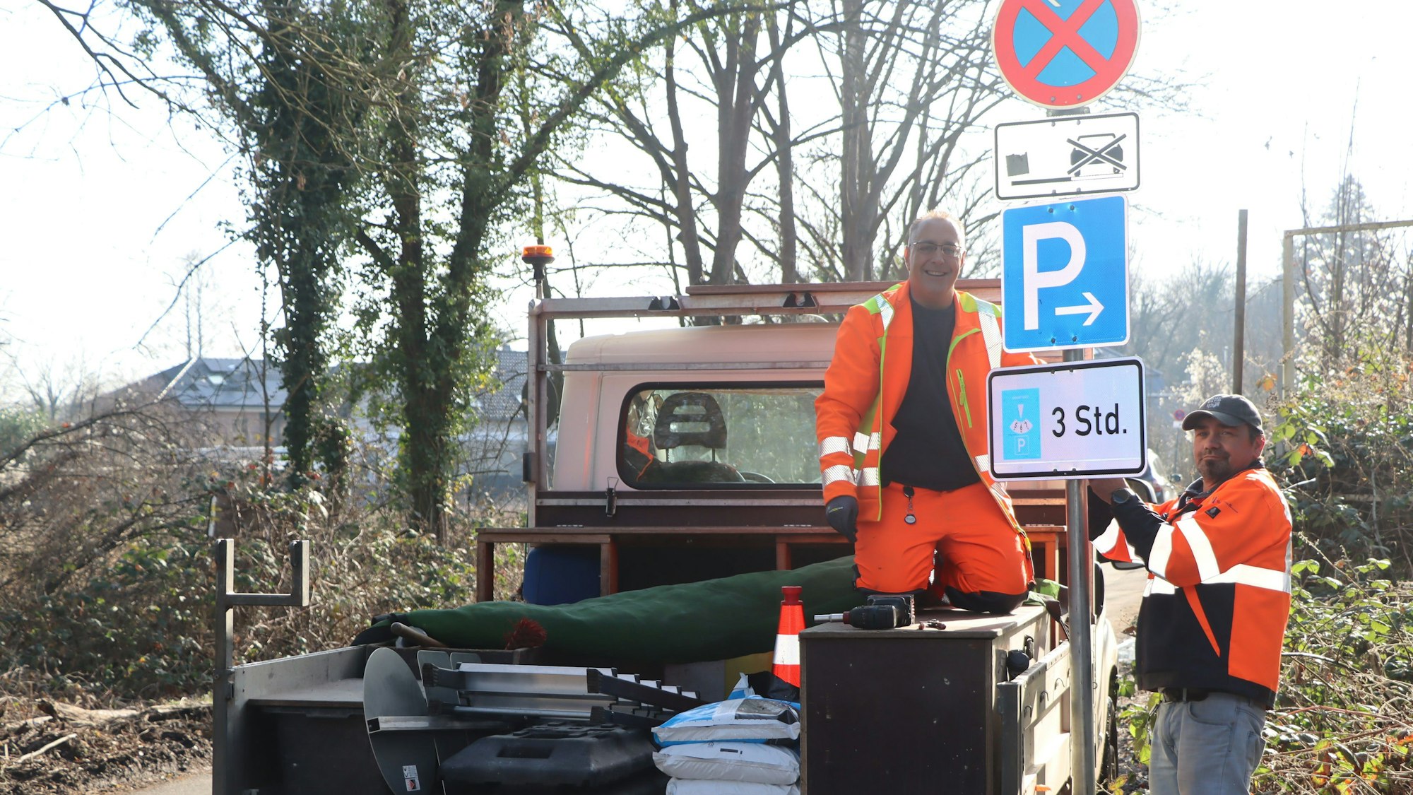 Zwei Männer stellen ein Schild auf.