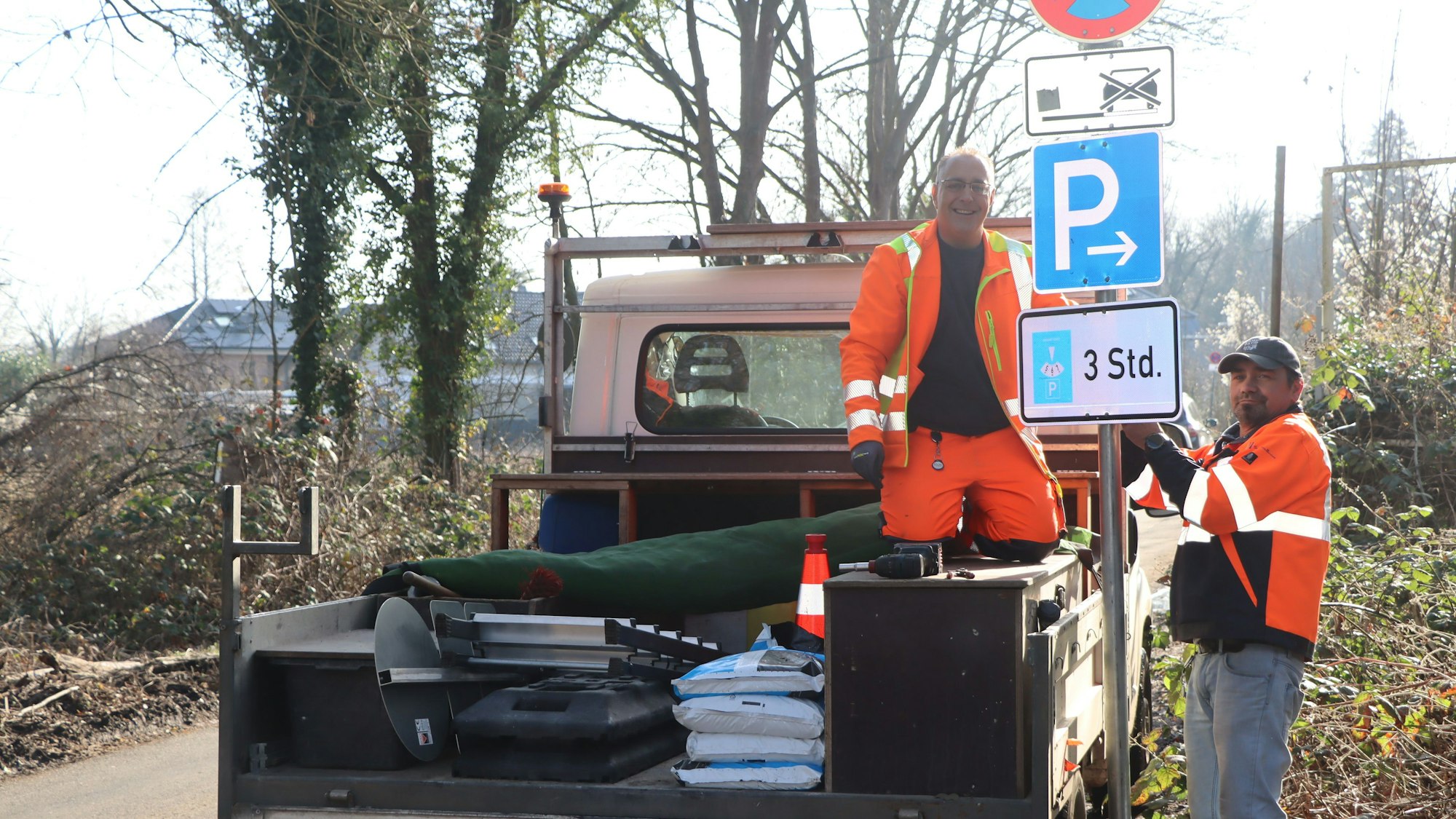 Das Bild zeigt Arbeiter an einem, einer auf einem LKW, die an den erwähnten Schildern werkeln.