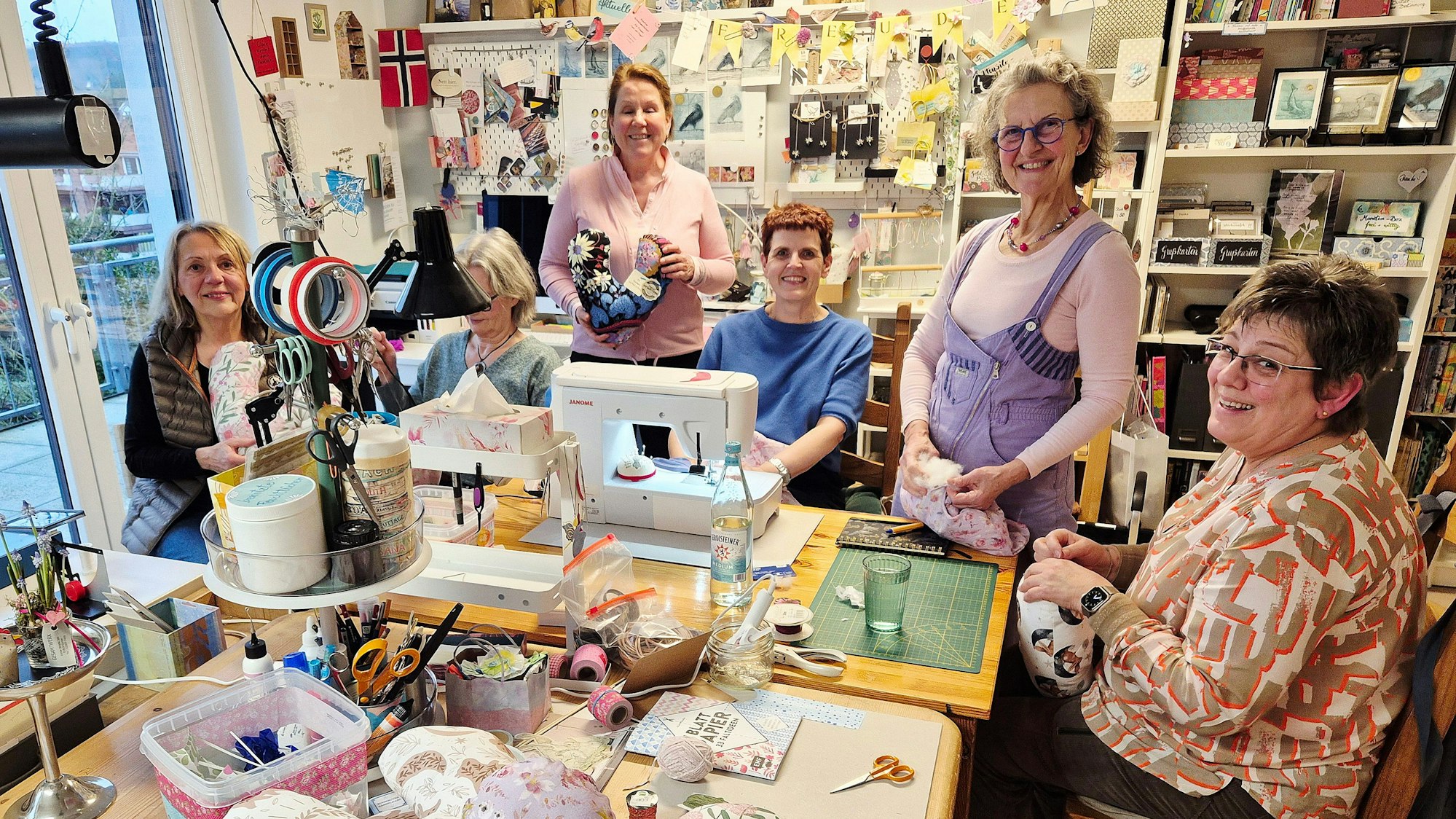 Sechs Frauen nähen, schneidern und stopfen.