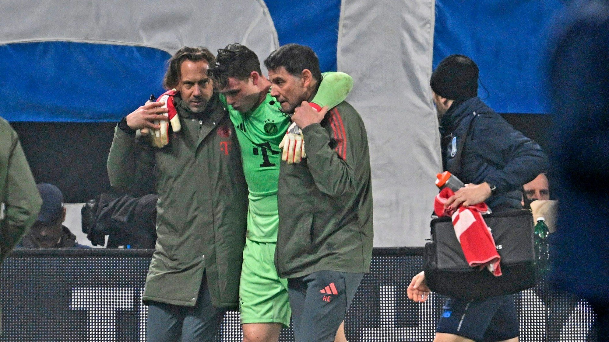 Jonas Urbig wird von zwei Betreuern gestützt.