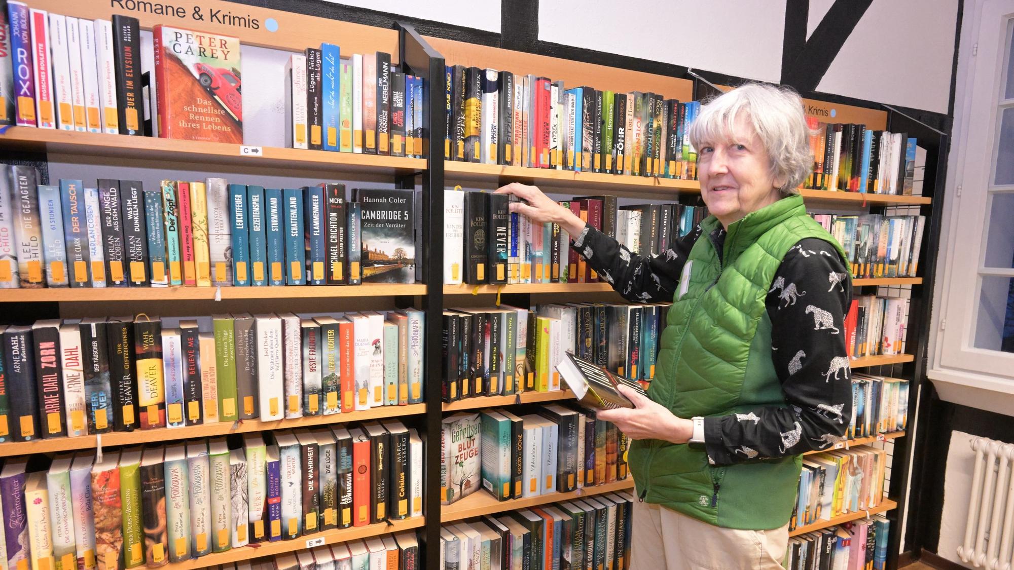Eine Frau steht vor einem Bücherregal in einer Bücherei.