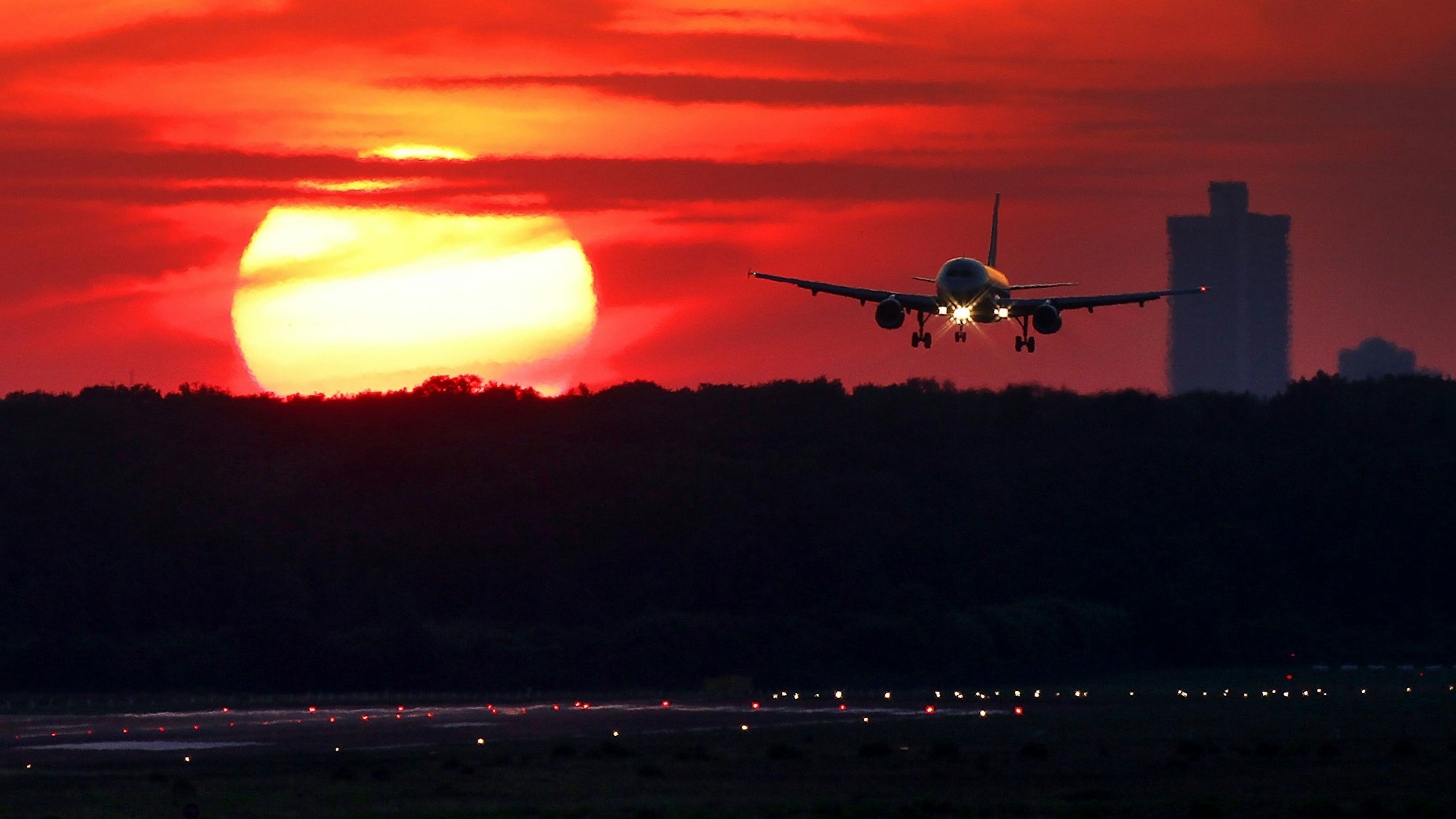 Ein Flugzeug landet vor untergehender Sonne auf dem Flughafen Köln-Bonn.