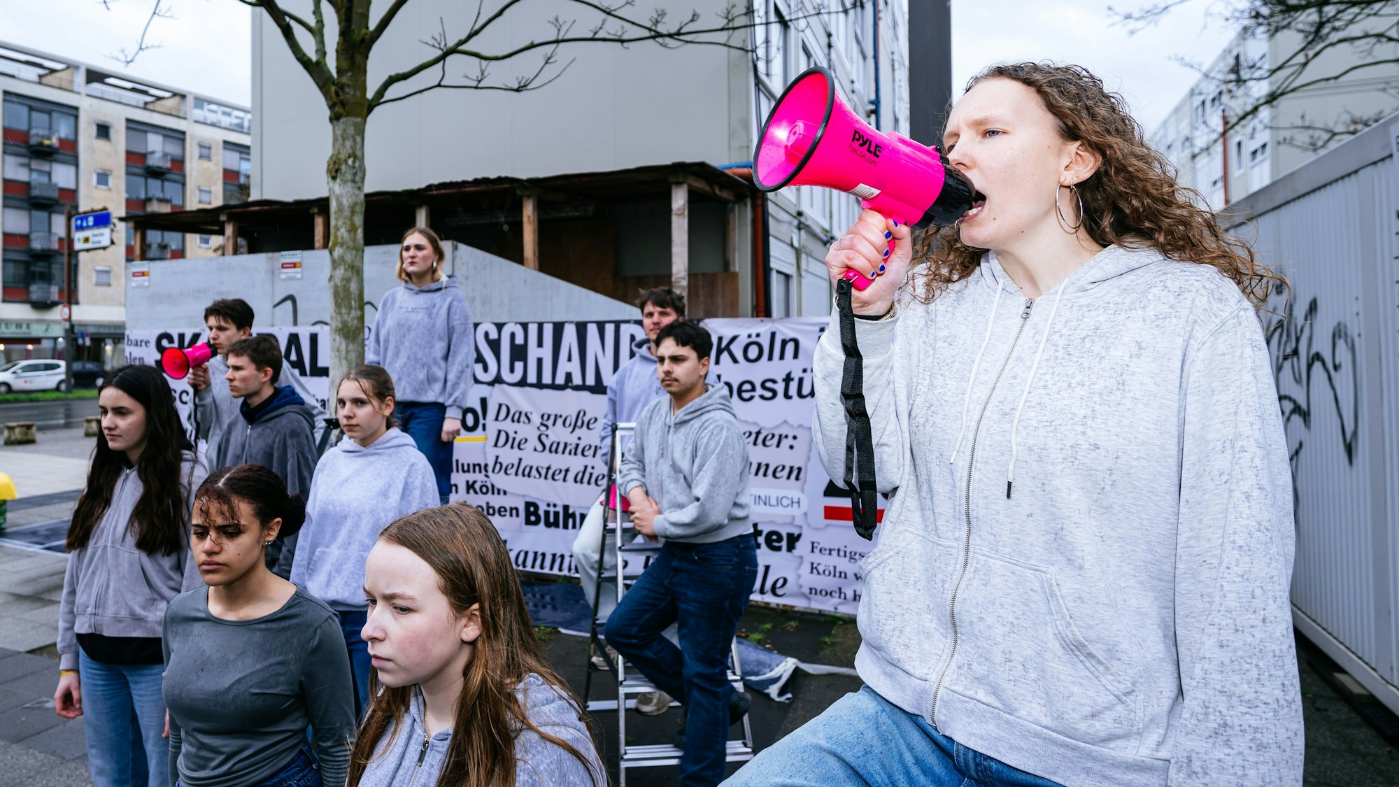 Zu sehen sind junge Menschen am Bauzaun der Oper.