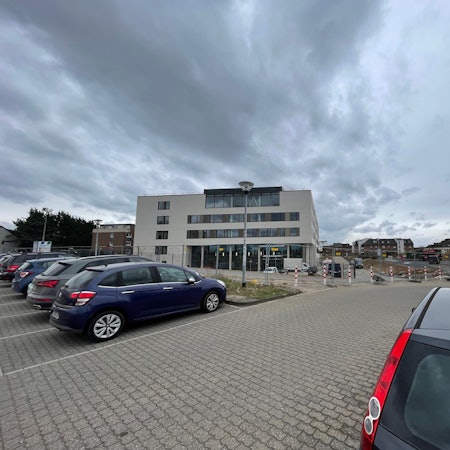 Blick auf das neue Euskirchener Rathaus: Im Vordergrund parken Autos auf einem Platz.