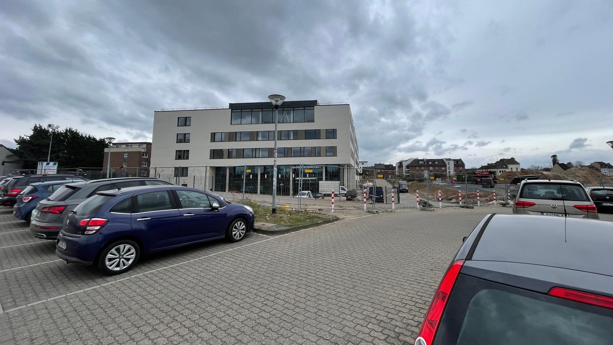 Blick auf das neue Euskirchener Rathaus: Im Vordergrund parken Autos auf einem Platz.