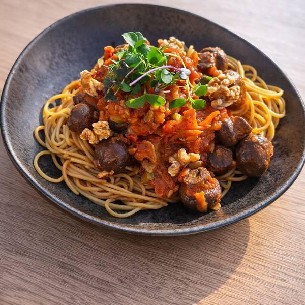 Spaghetti mit Walnuss-Pilz-Bolognese auf einem dunklen Teller.