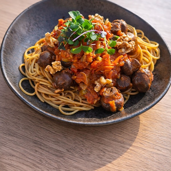 Spaghetti mit Walnuss-Pilz-Bolognese auf einem dunklen Teller.