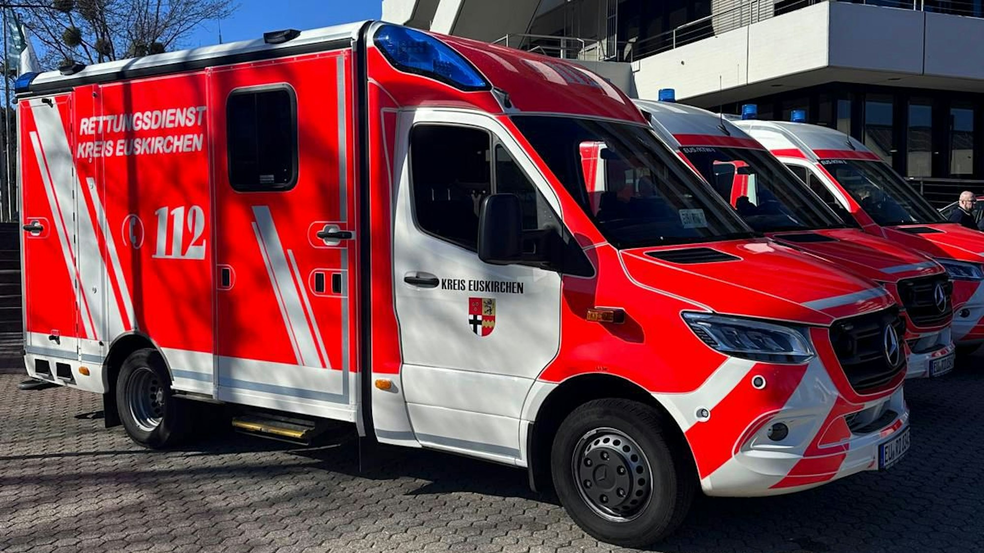 Ein Rettungswagen und zwei Krankentransportwagen stehen vor dem Kreishaus in Euskirchen.