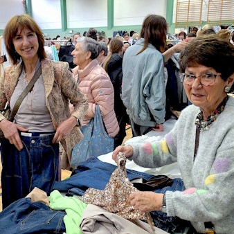Zwei Frauen stehen in Mechernich an einem Flohmarktstand mit Kleidung.