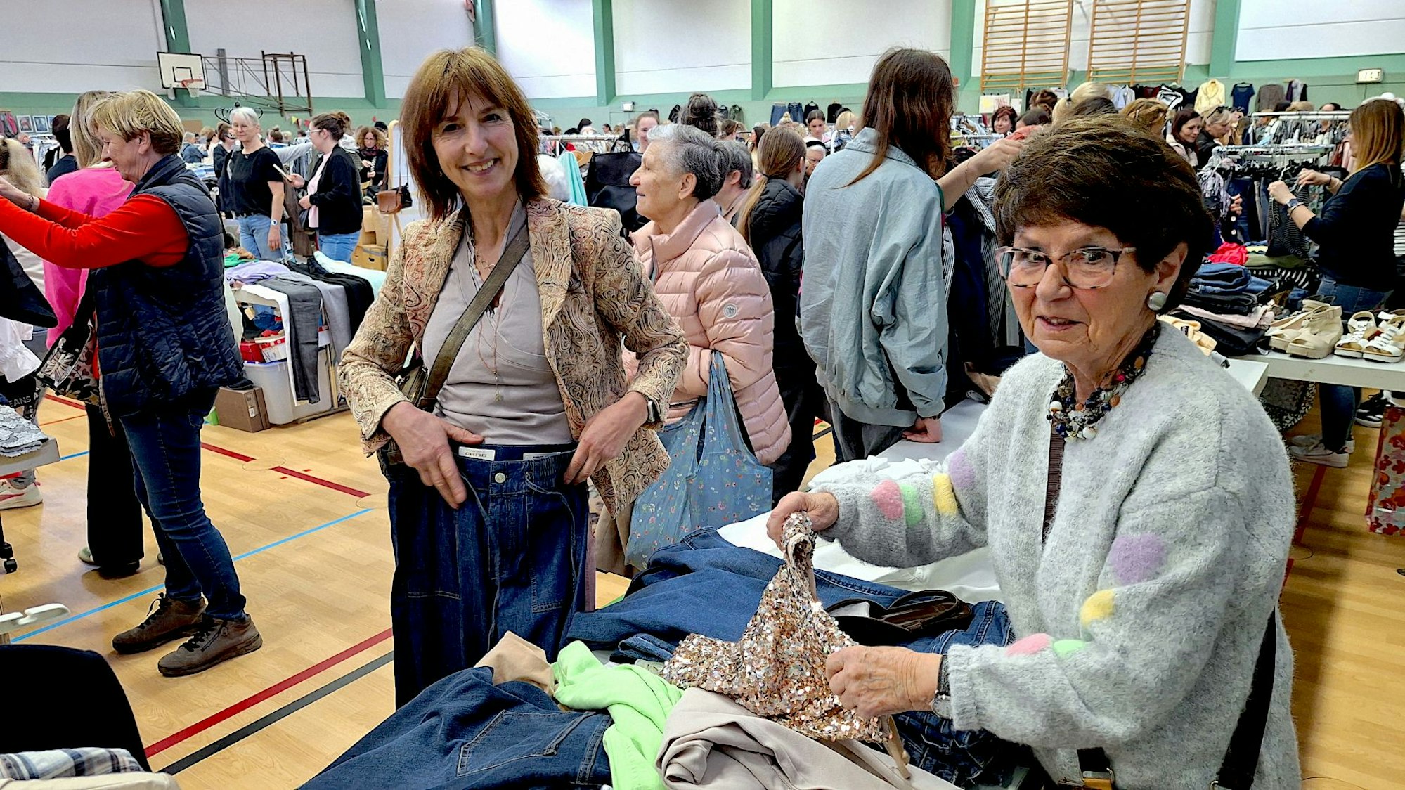 Zwei Frauen stehen in Mechernich an einem Flohmarktstand mit Kleidung.