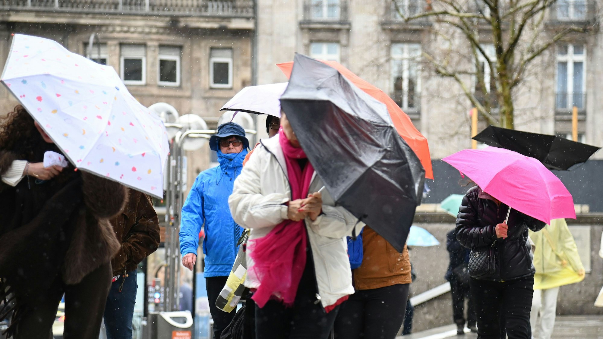 Menschen schützen sich auf der Domplatte in Köln vor Regen und Wind. (Archivfoto)