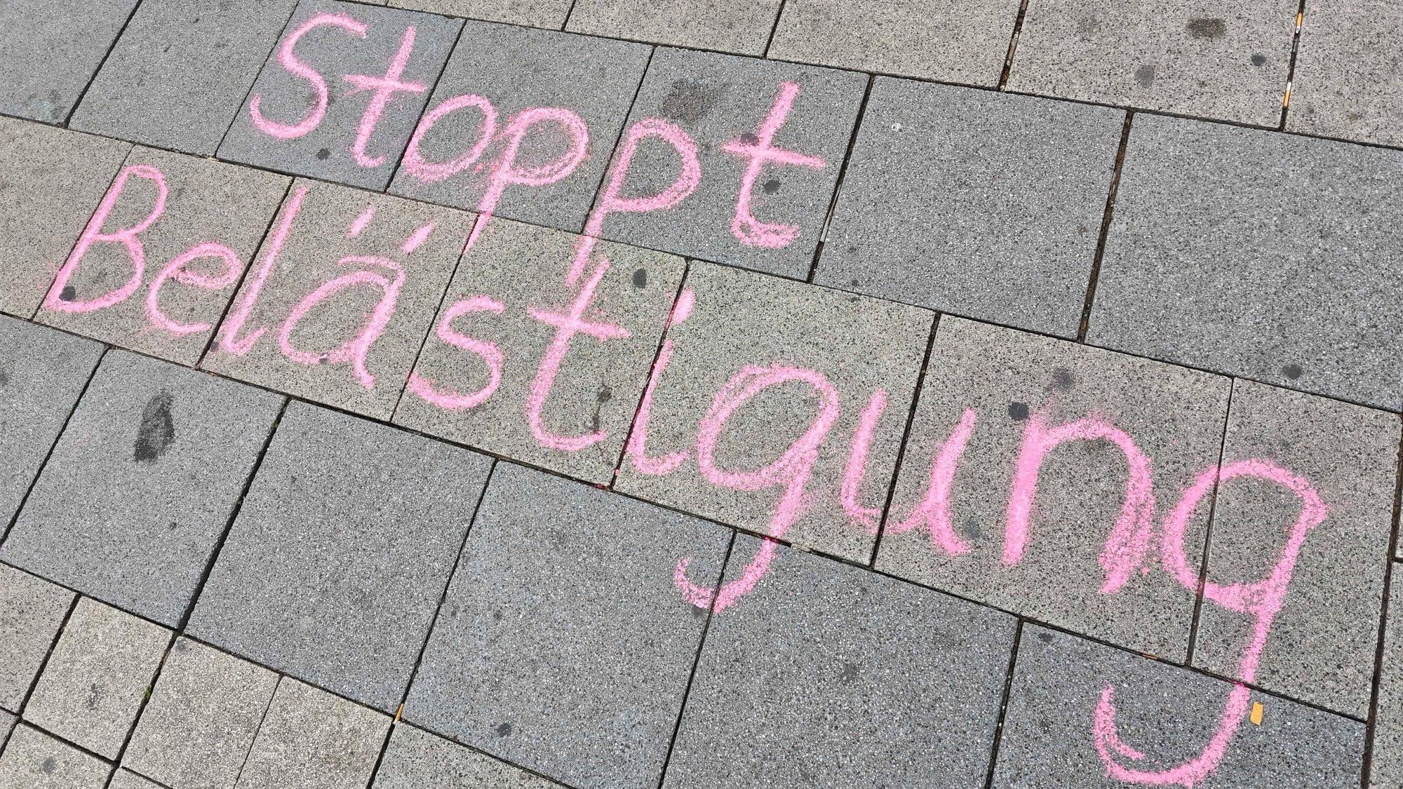 "Stoppt Belästigung" steht mit Kreide geschrieben auf einem Gehweg.