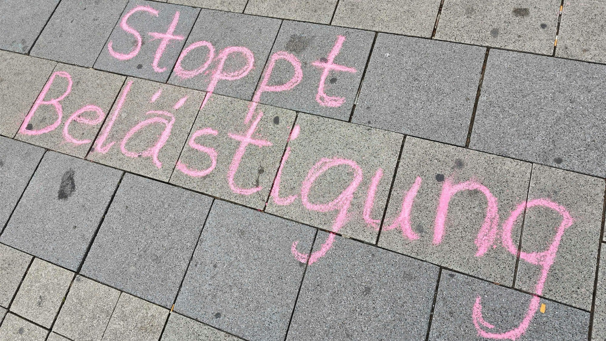"Stoppt Belästigung" steht mit Kreide geschrieben auf einem Gehweg.