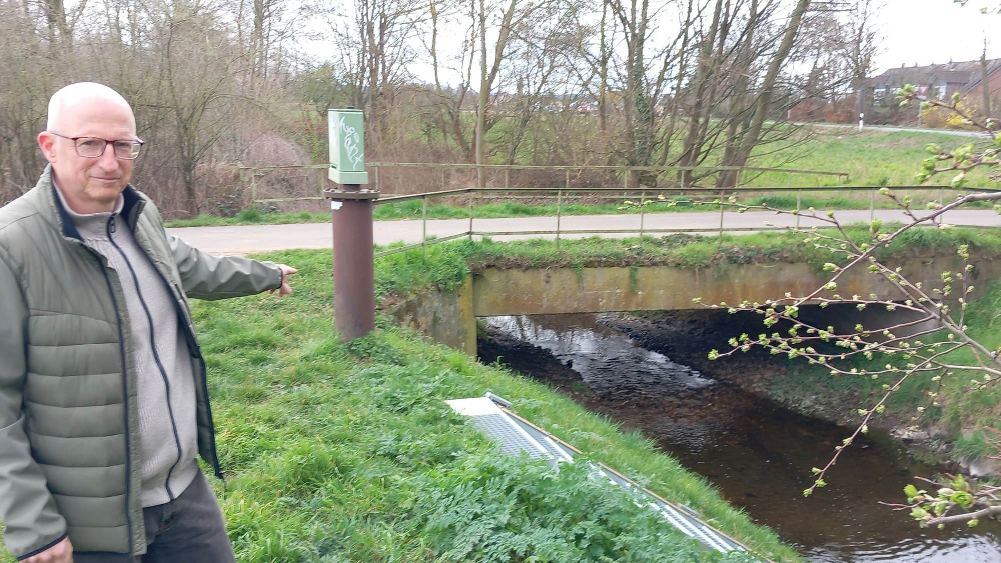 Thorsten Krause zeigt am Pegel Essig, wo bei der Starkregenkatastrophe 2021 der Schwimmer stand, die Skala an der Treppe war überflutet.
