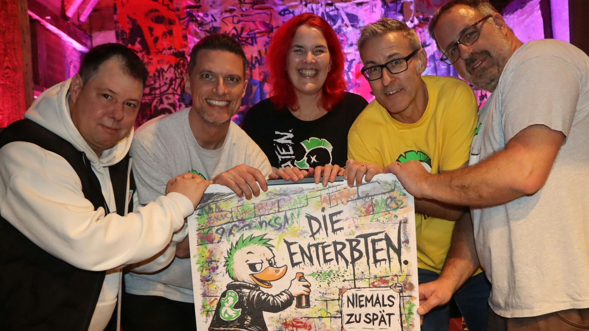 Das Foto zeigt Menschen, die ein großes Musikcover hochhalten.