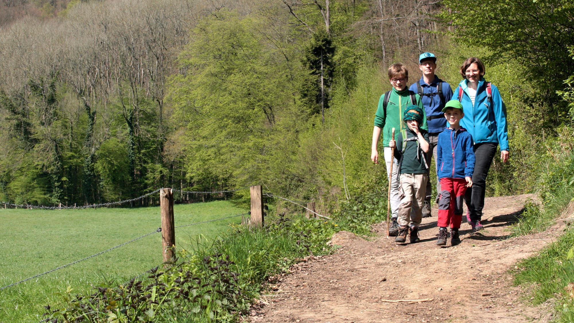 Eine Familie geht auf einem Wanderweg bei Odenthal-Altenberg durch die Frühlingssonne.