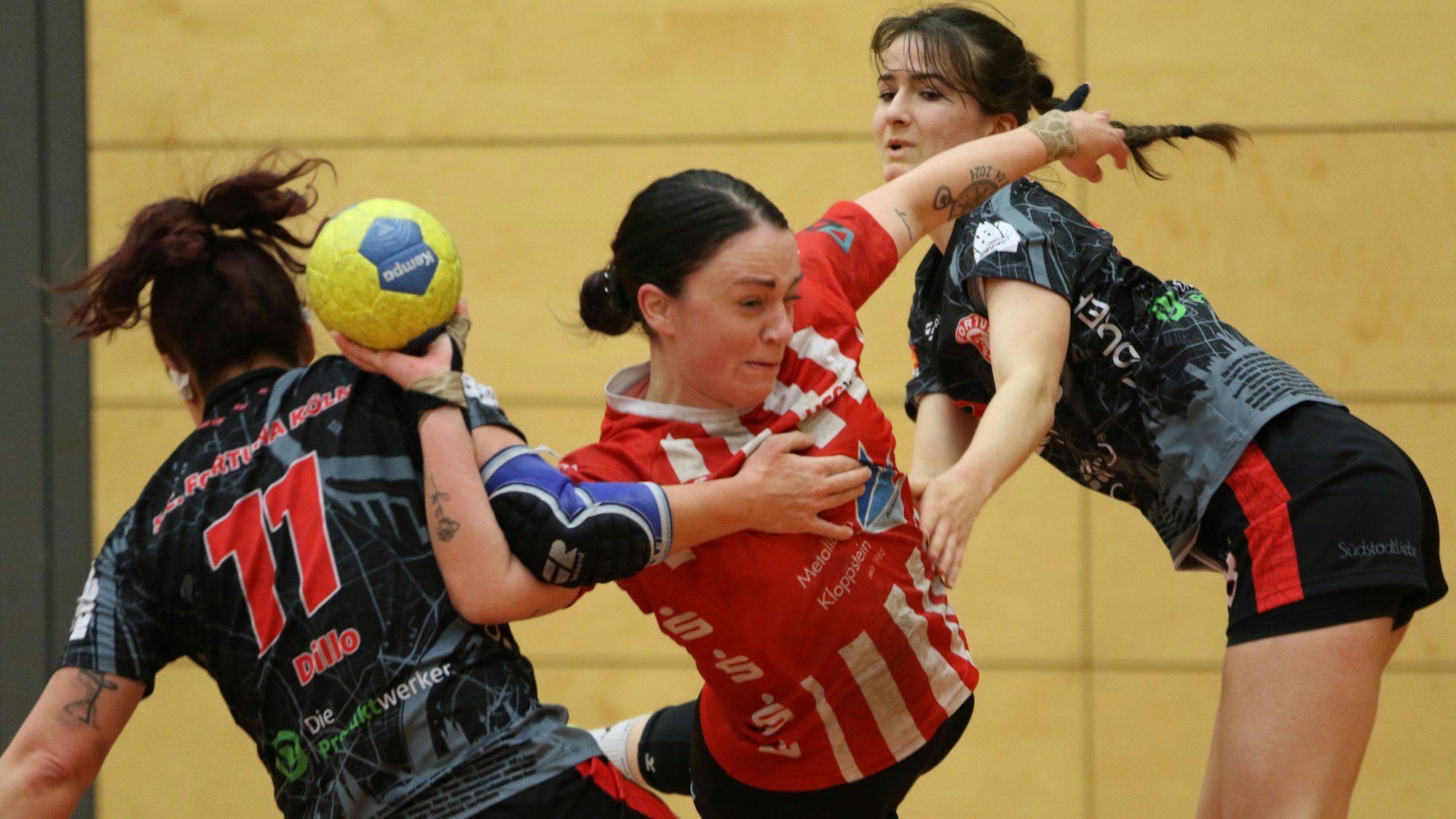 Svenja Bank wird von zwei Gegenspielerinnen am Wurf gehindert und zieht einen Siebenmeter.