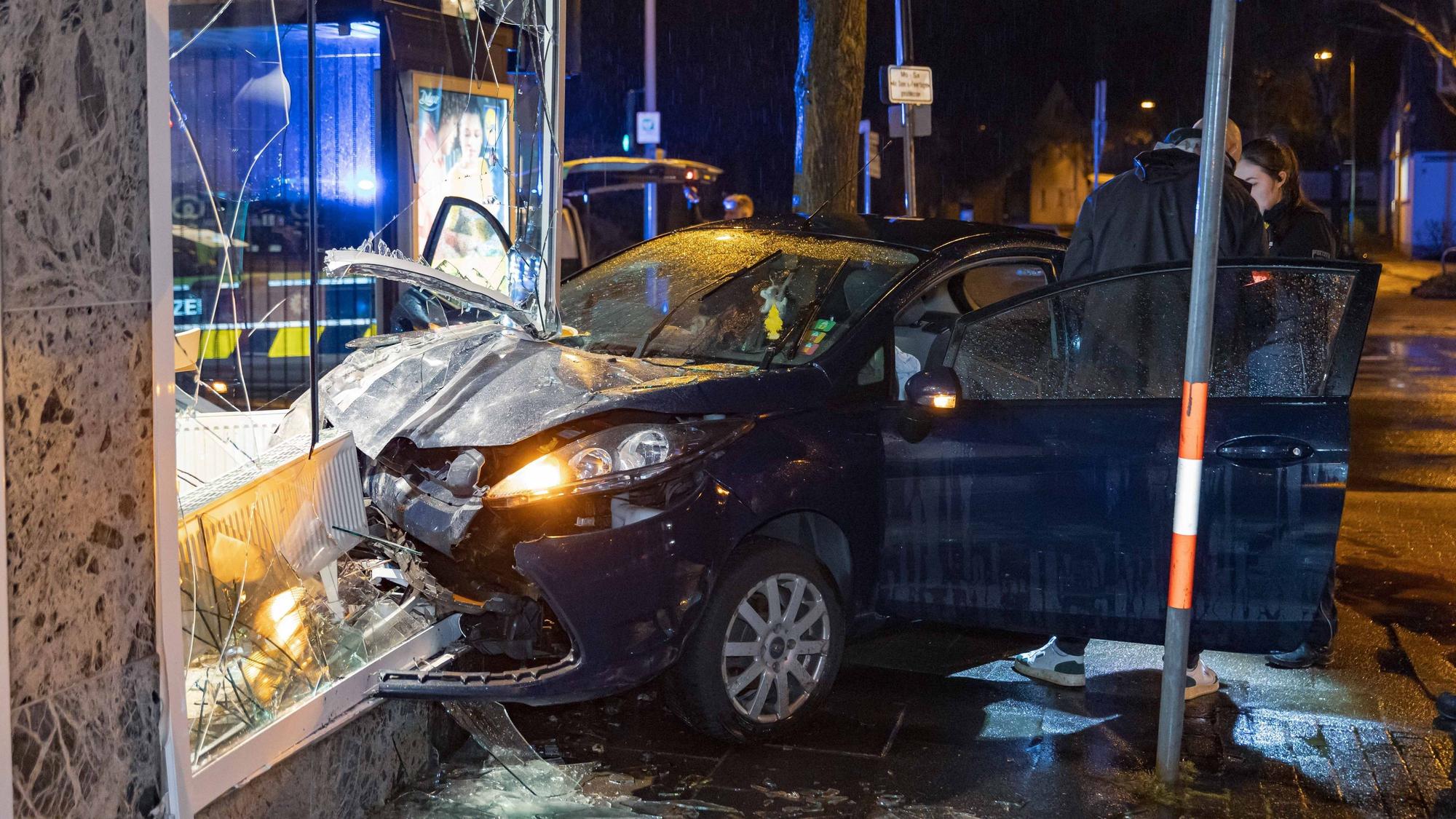 Ermittler stehen im März dieses Jahres an der Unfallstelle, wo ein Fahrer mit seinem Auto in das Schaufenster einer Leverkusener Bäckerei gekracht ist.