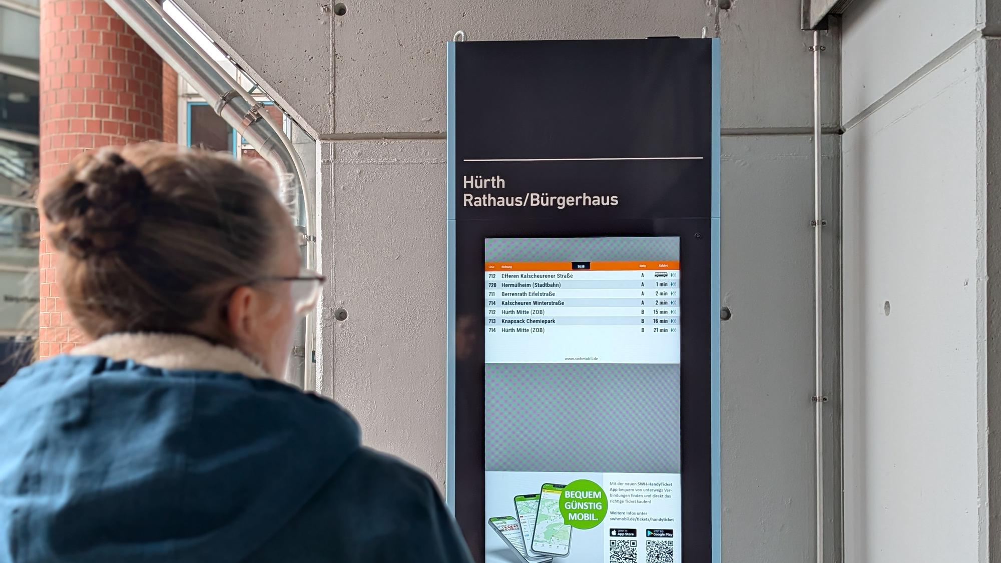 Das Foto zeigt eine Passantin vor der elektronischen Fahrplan-Stele am Rathaus.