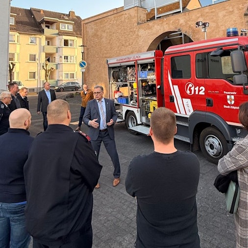 Das Feuerwehrauto steht vor der Martinskirche. Im Vordergrund sind Mencehn von hinten zu sehen, mittig vor dem Auto steht der Zülpicher Bürgermeister Ulf Hürtgen.