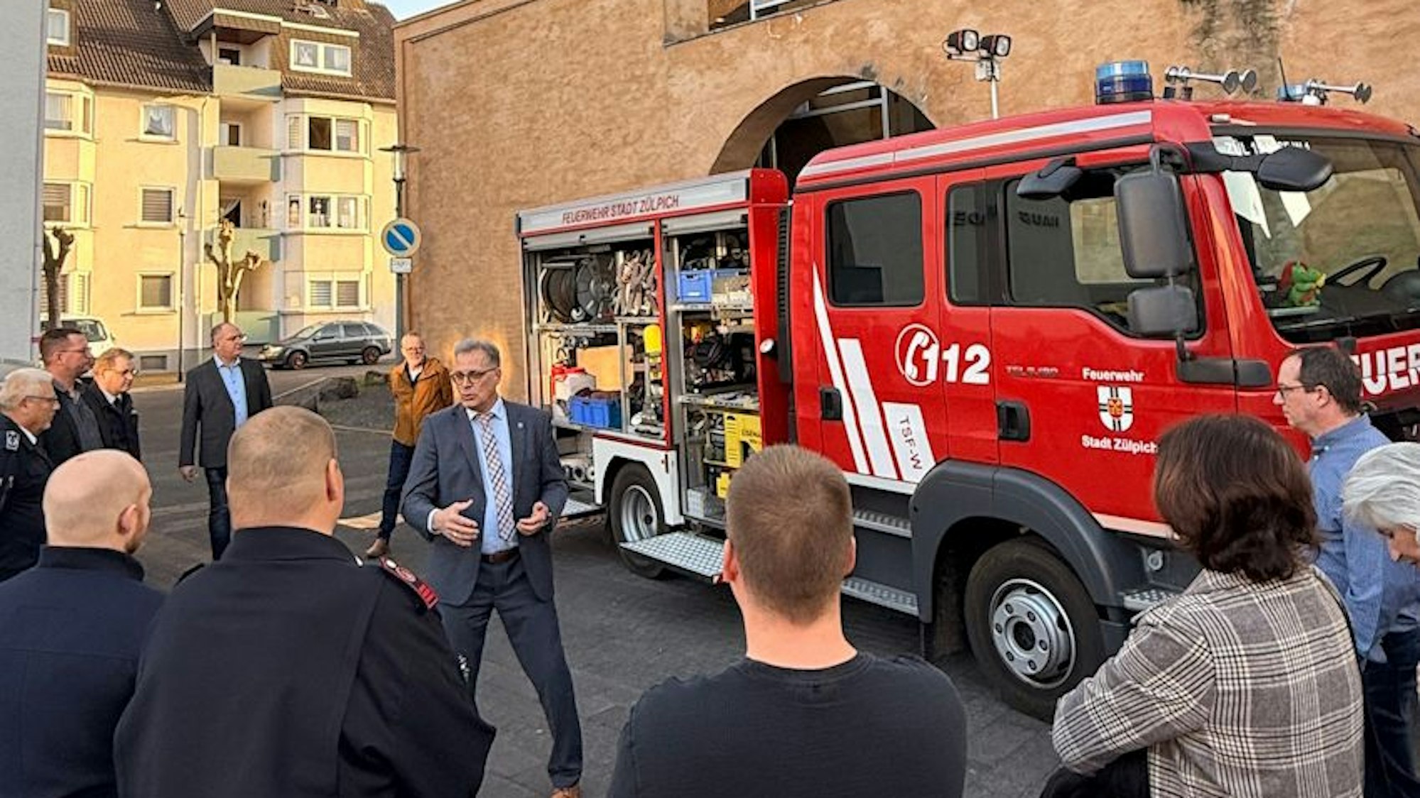 Das Feuerwehrauto steht vor der Martinskirche. Im Vordergrund sind Mencehn von hinten zu sehen, mittig vor dem Auto steht der Zülpicher Bürgermeister Ulf Hürtgen.