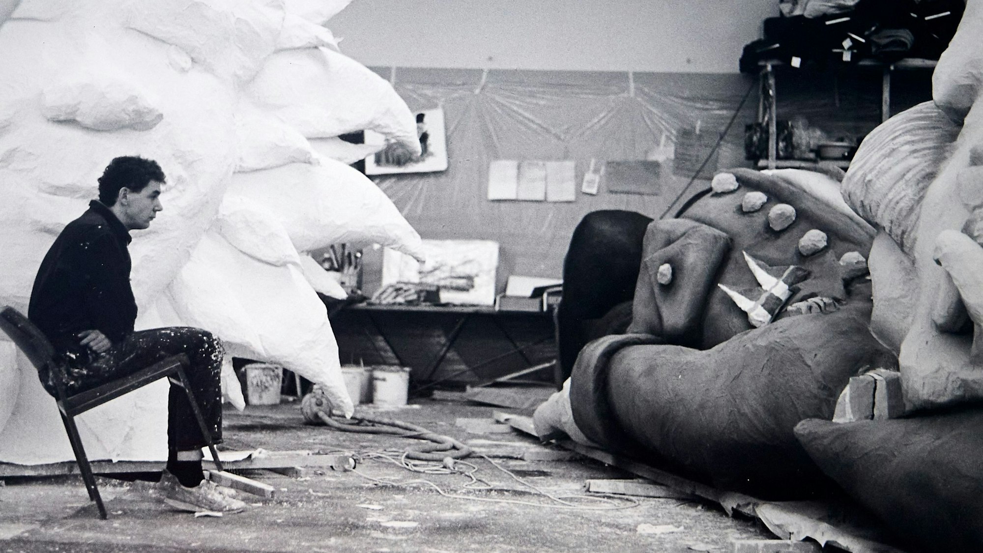 Ein altes Schwarzweiß-Bild zeigt Tilly, der auf einem Stuhl gegenüber einer unfertigen Pappfigur sitzt,