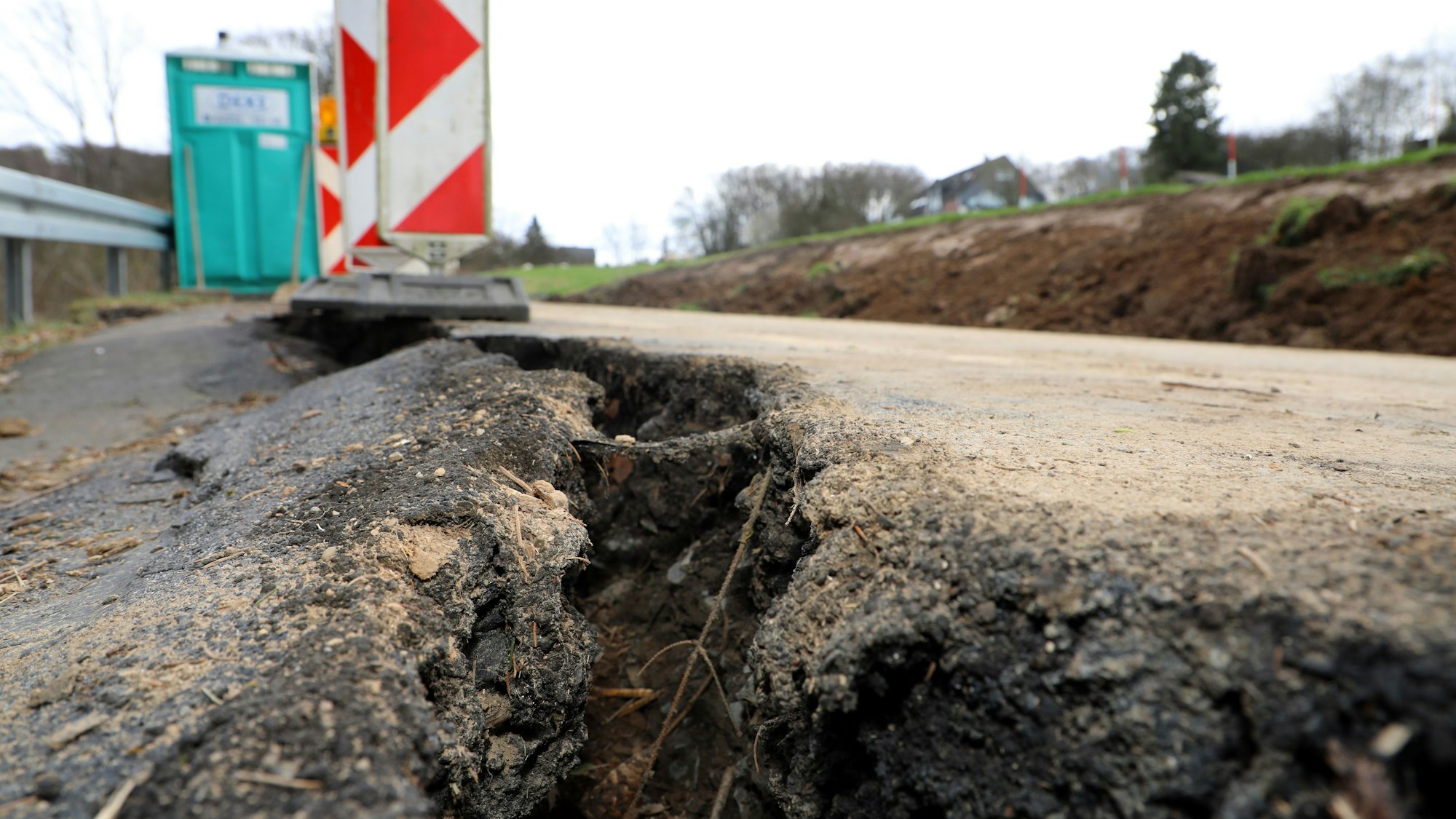 In einer Straße klafft ein großer Riss im Asphalt. De Straße ist abgesackt.