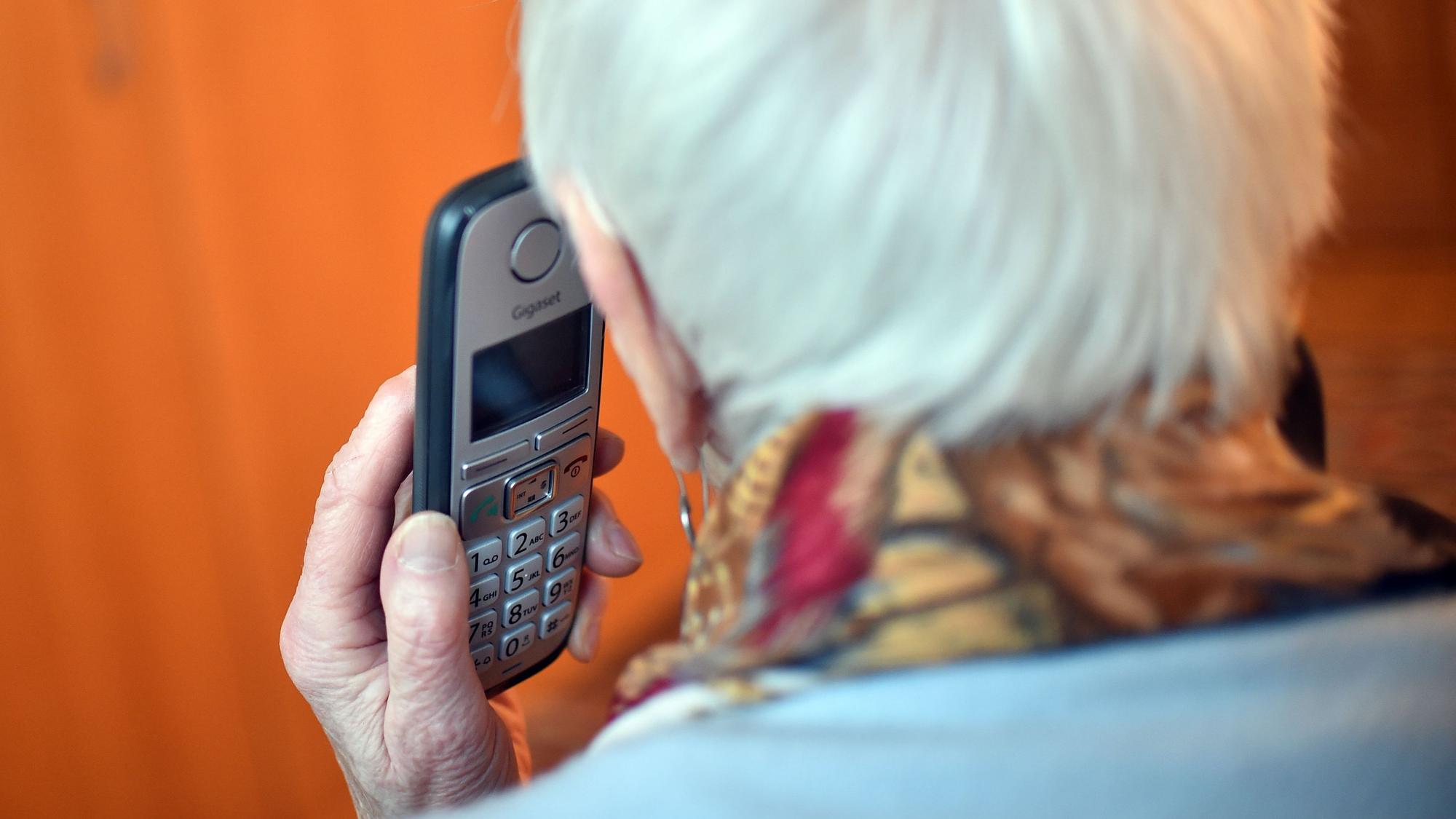 Eine Seniorin hält ein Handy an ihr Ohr (gestellte Szene).