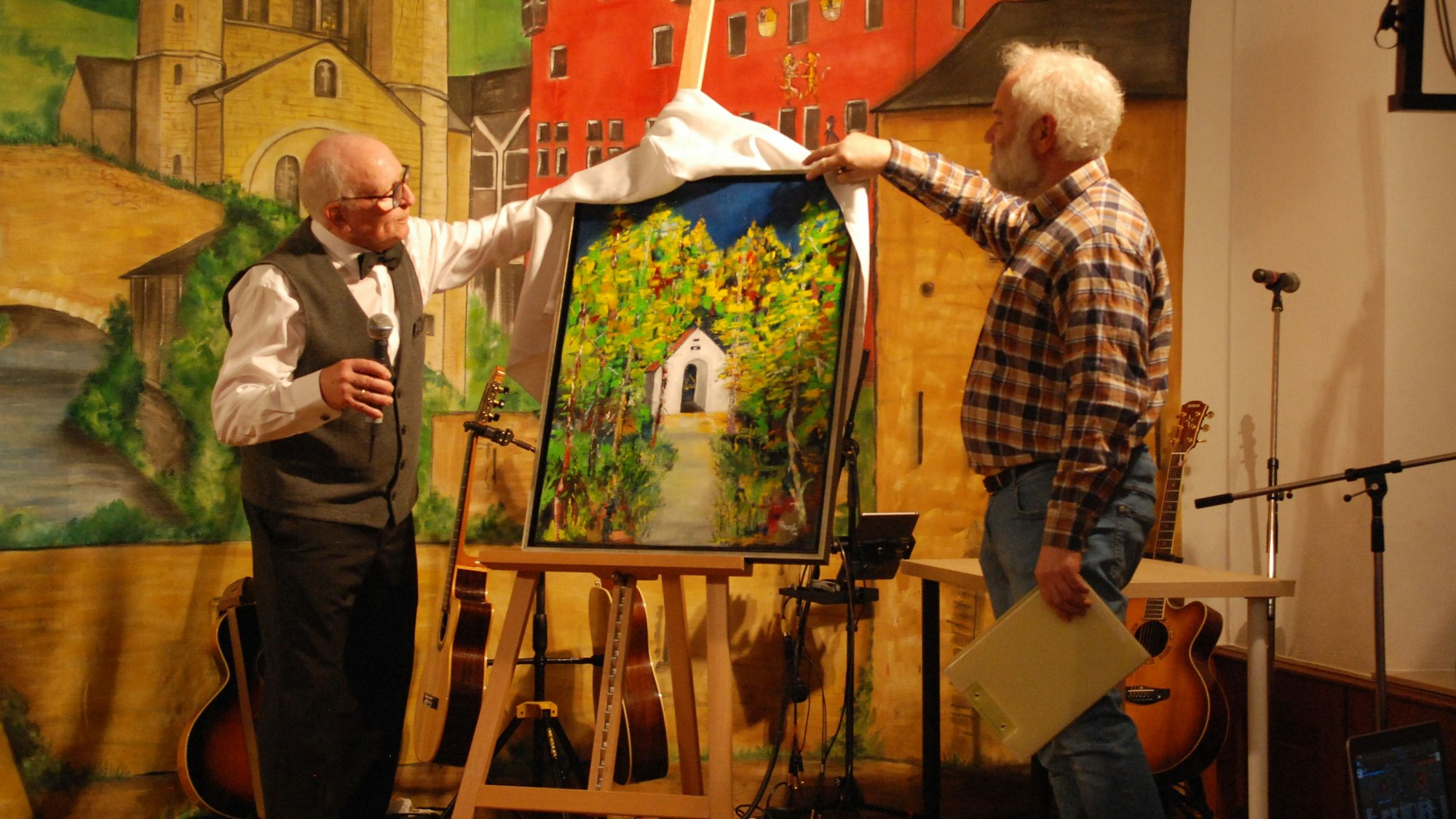 Das Bild steht auf einer Staffelei, die Männer ziehen ein weißes Tuch weg.