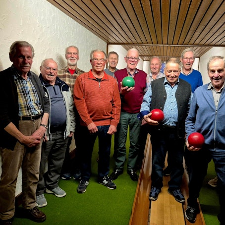 Blick auf zwölf Männer auf einer Kegelbahn.