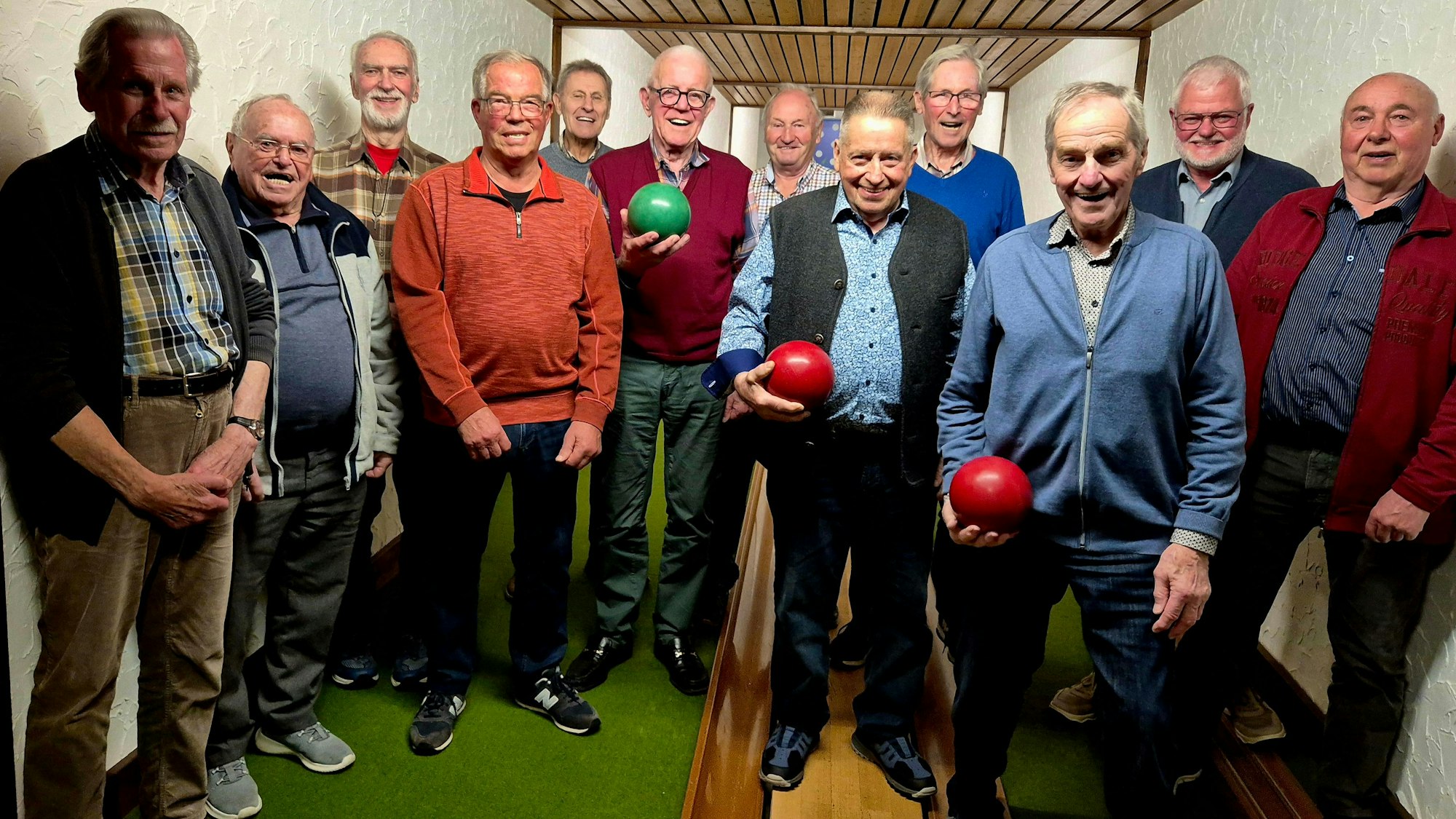 Blick auf zwölf Männer auf einer Kegelbahn.