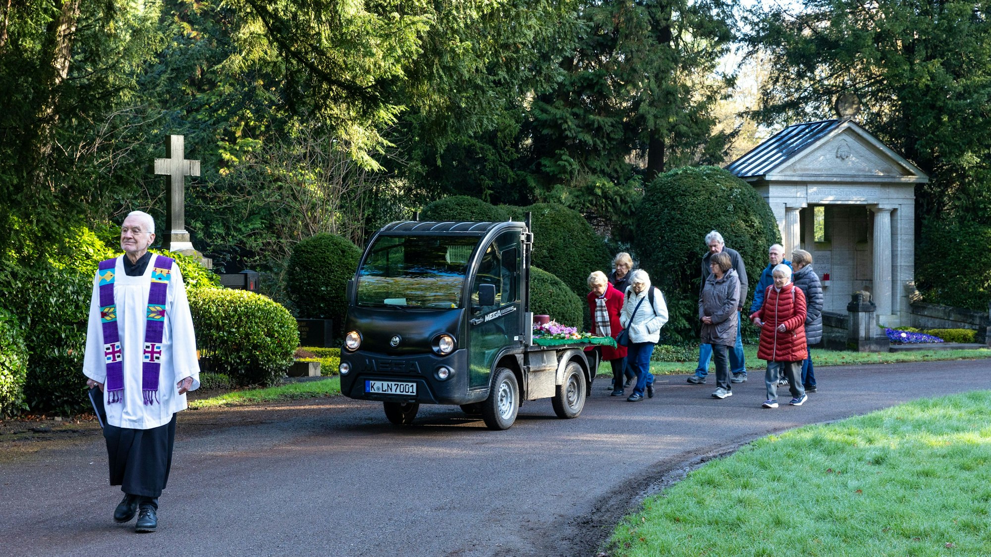 Eine kleine Begleitergruppe folgt auf dem Südfriedhof dem Elektromobil mit der Urne.Vorneweg geht Pfarrer Johannes Krautkrämer.