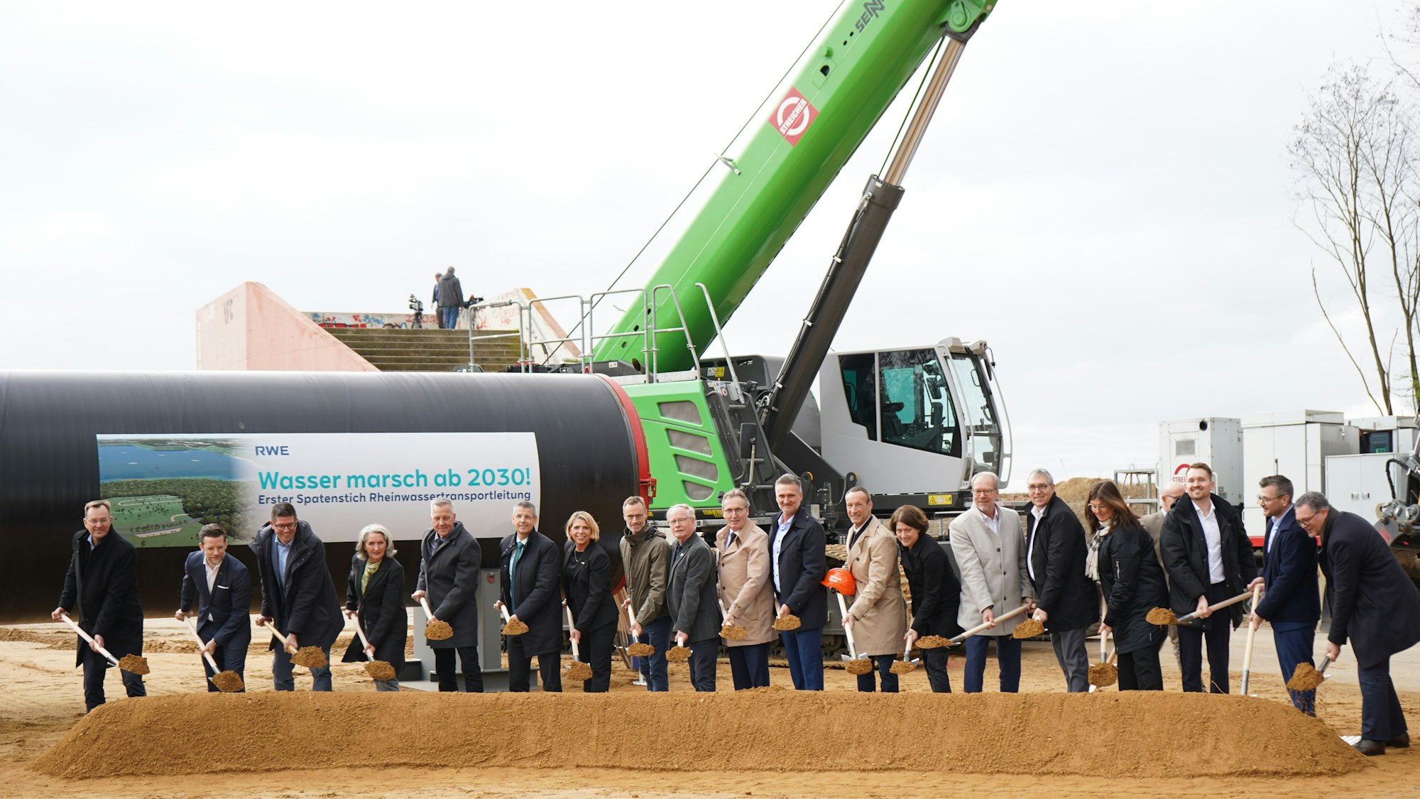 Das Bild zeigt die Vertreter mit Spaten in der Hand, hinter ihnen eines der Rohre.