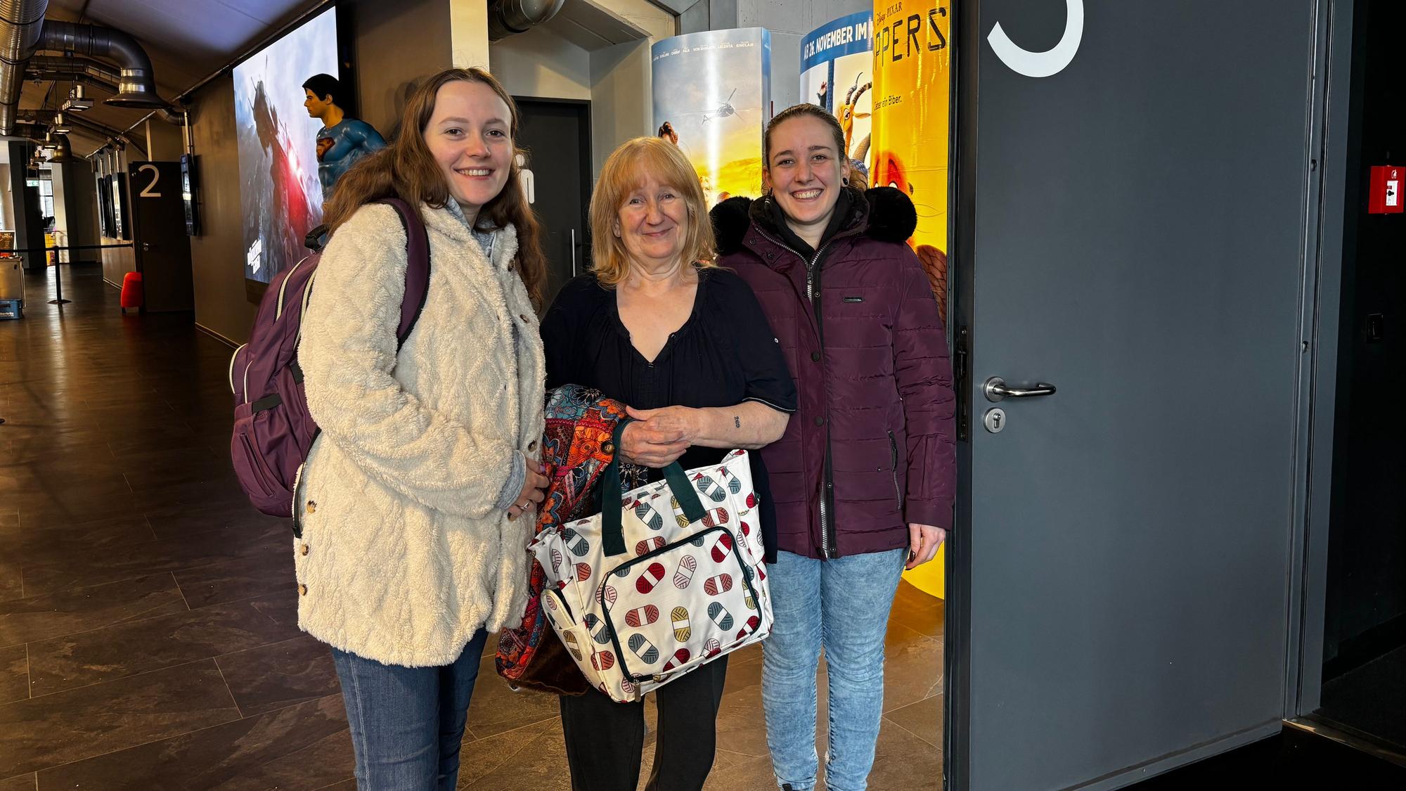 Die drei Frauen stehen im Foyer des Kinos und lächeln in die Kamera. Sybille Klockner hält eine Häkeltasche in der Hand.