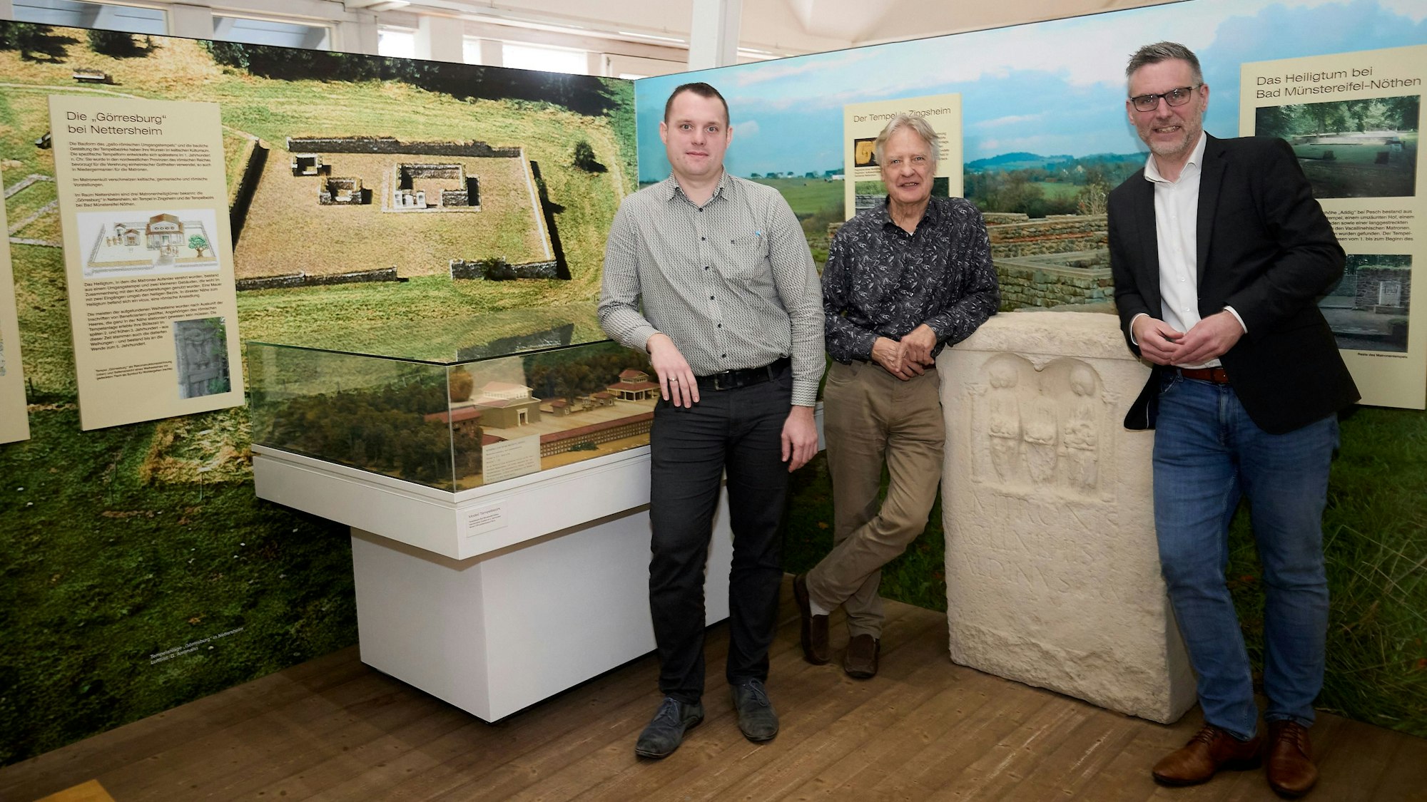 Alexander Mauel (v.l.), Joachim Starke und Norbert Crump stehen vor Stellwänden mit Nettersheimer Motiven.