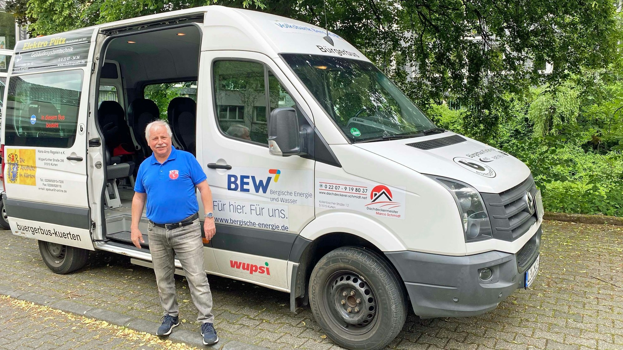 Ein Mann steht vor dem grauen Bürgerbus.