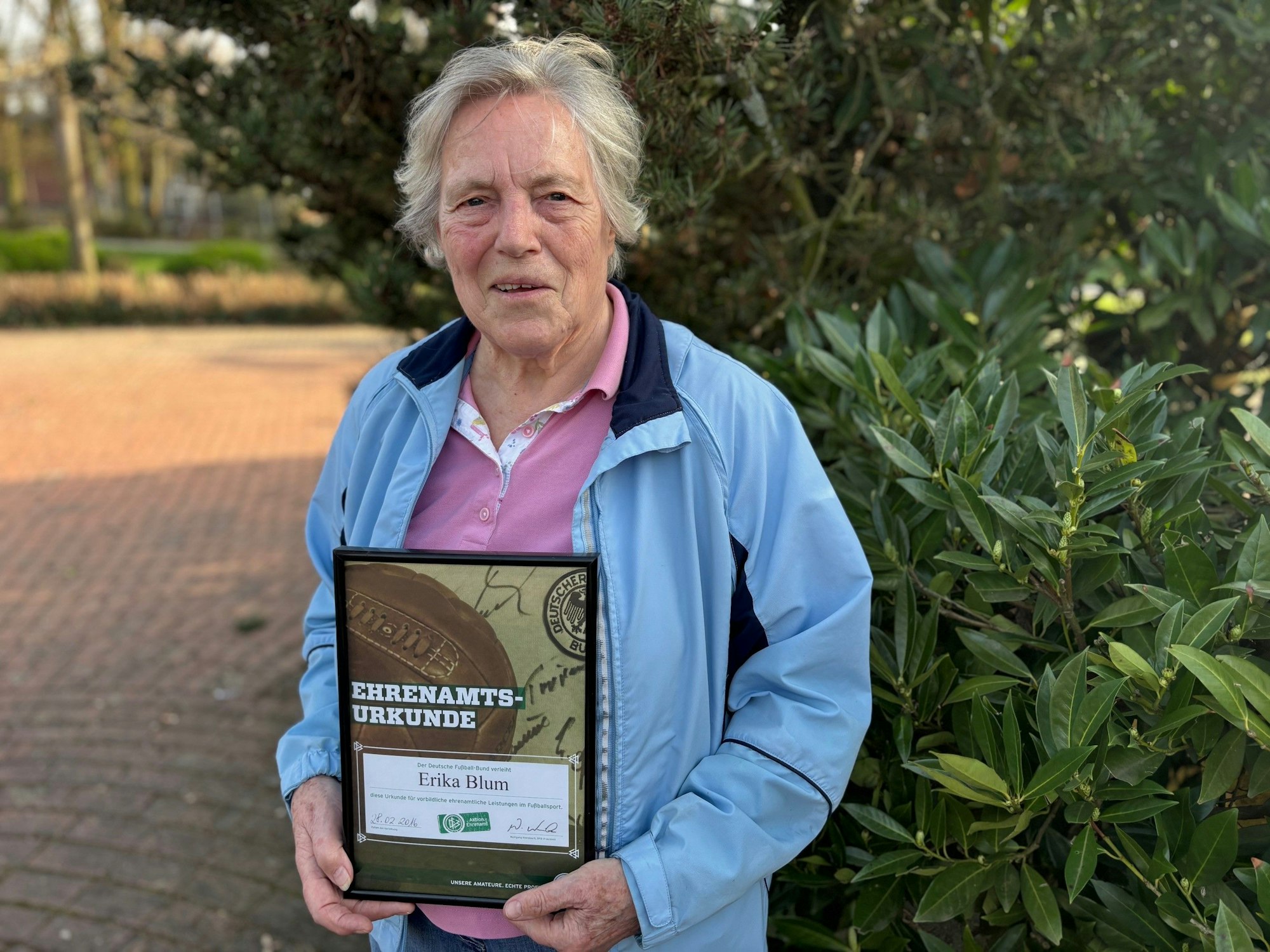 Auf dem Bild ist eine ältere Dame mit einer Urkunde zu sehen.