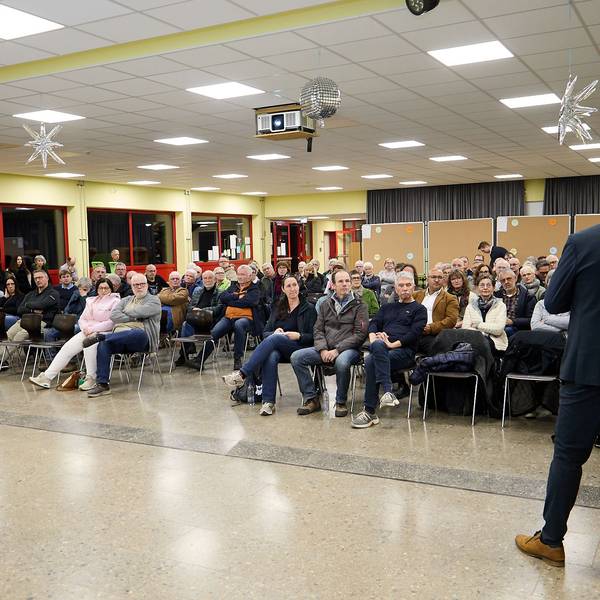 Die Aufnahme zeigt die sitzenden Teilnehmer in einem Saal der Gemünder Grundschule. Vor ihnen steht, von hinten fotografiert, Bürgermeister Ingo Pfennings.