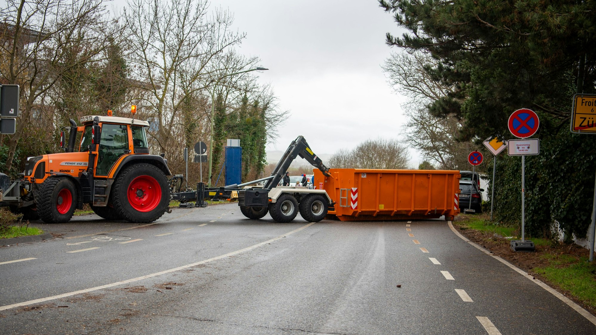 Ein Traktor setzt einen Container ab, um eine Zufahrtsstraße zum Zülpicher Karnevalszug zu sperren.